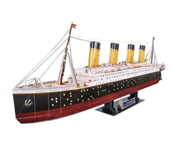 Model statku Titanic z papieru, na czarnym stojaku, białe tło.