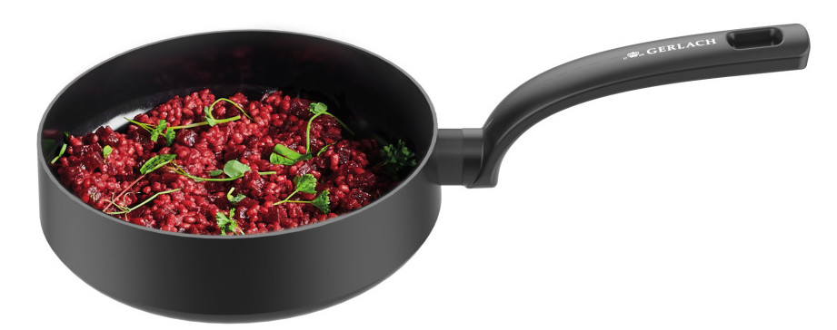 Czarna patelnia wypełniona czerwonym jedzeniem, z zielonymi dodatkami.