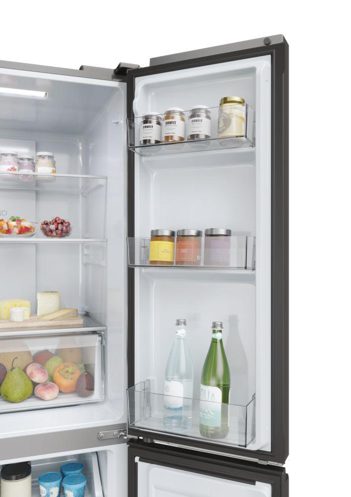 Kühlschrankinnenraum mit Regalen. Gläser, Flaschen, Obst und Gemüse sind sichtbar.