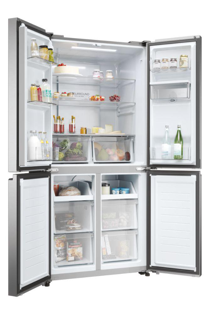 Offener Kühlschrank mit mehreren Regalen und Schubladen, gefüllt mit Lebensmitteln, einschließlich Produkten und Flaschen.