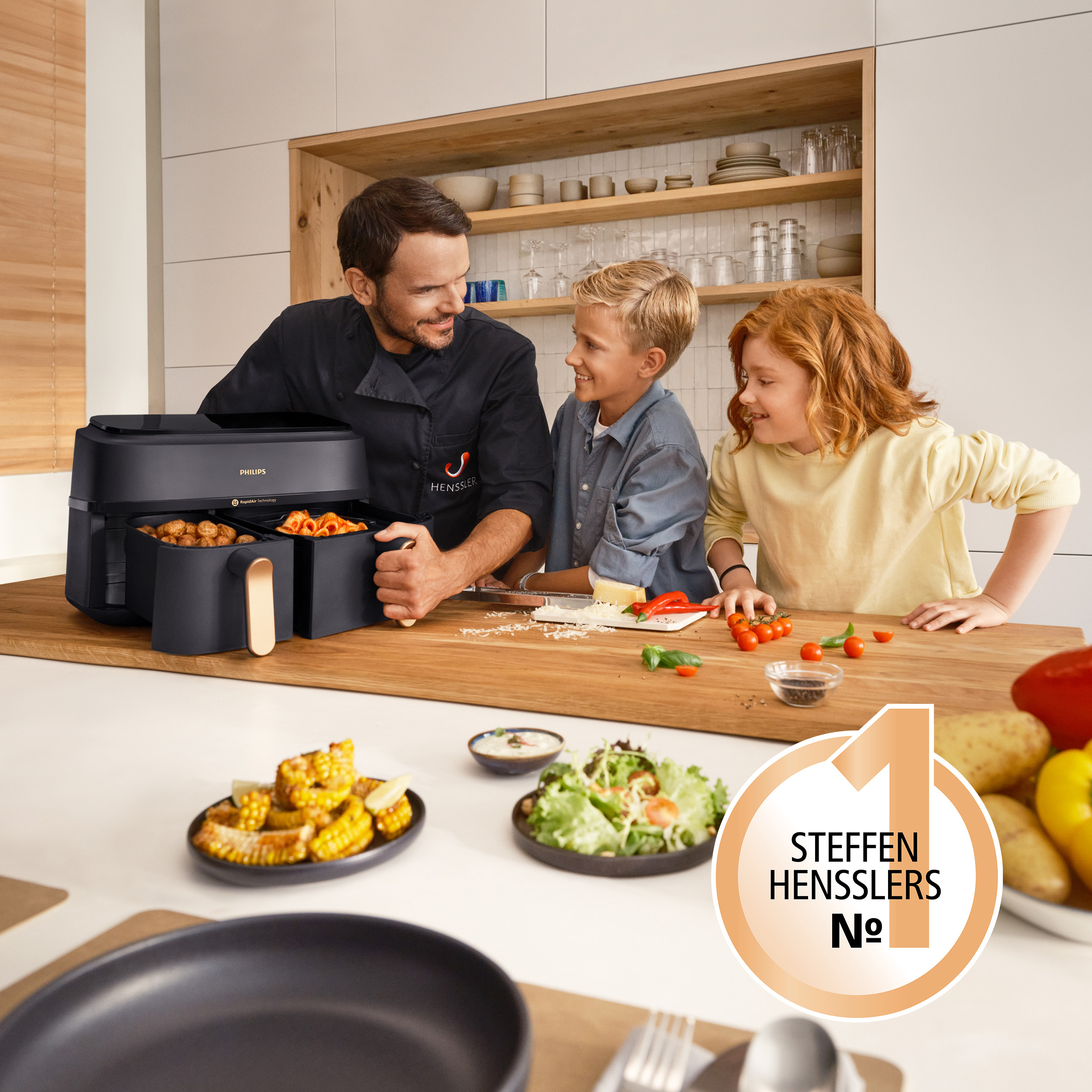 Uomo e due bambini guardano il cibo preparato in una friggitrice ad aria.