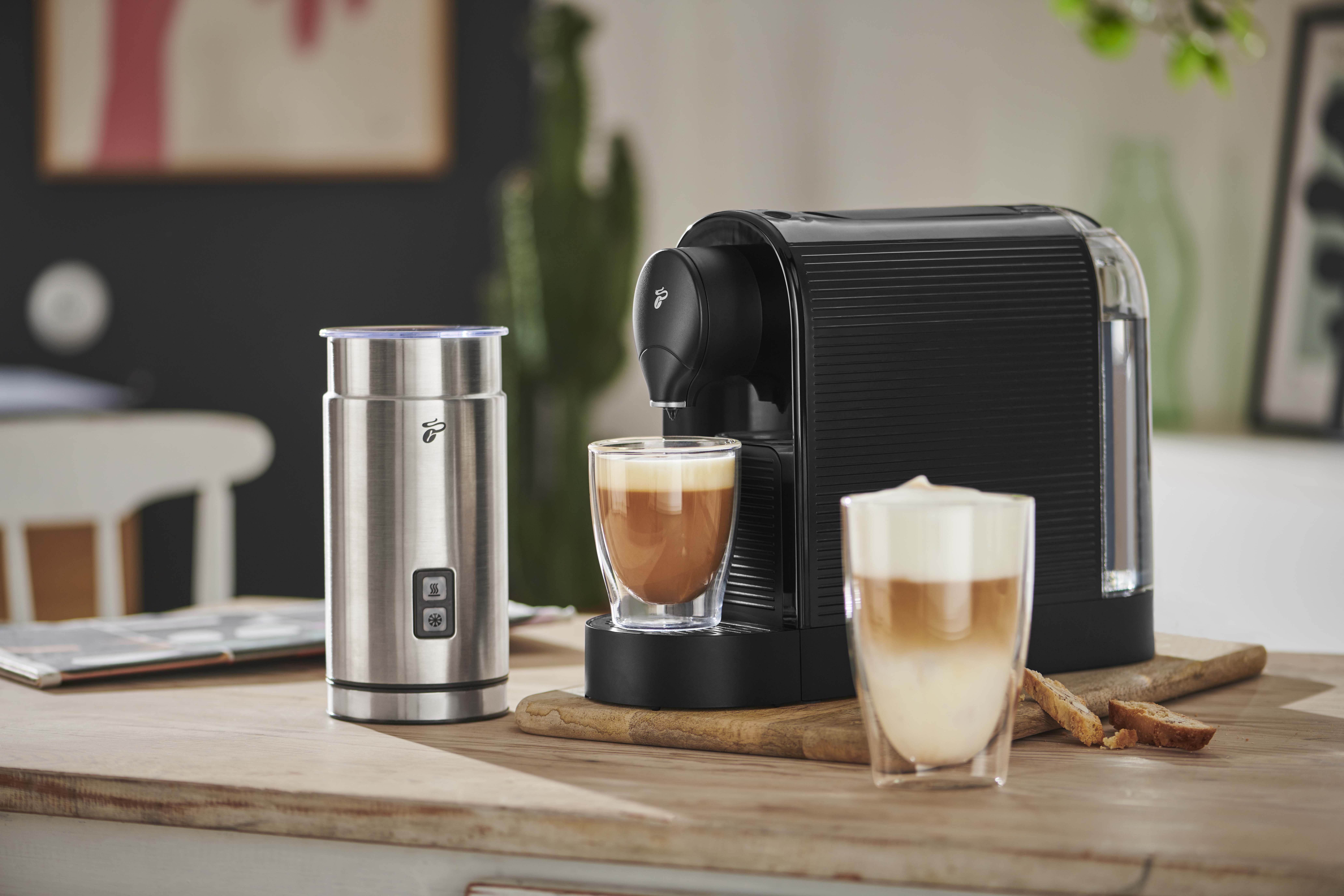 Latte yapan kahve makinesi. Gümüş köpürtücü, iki bardak, ahşap yüzey.