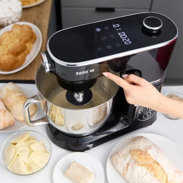 Czarny mikser stojący ze stalową misą; składniki na stole.