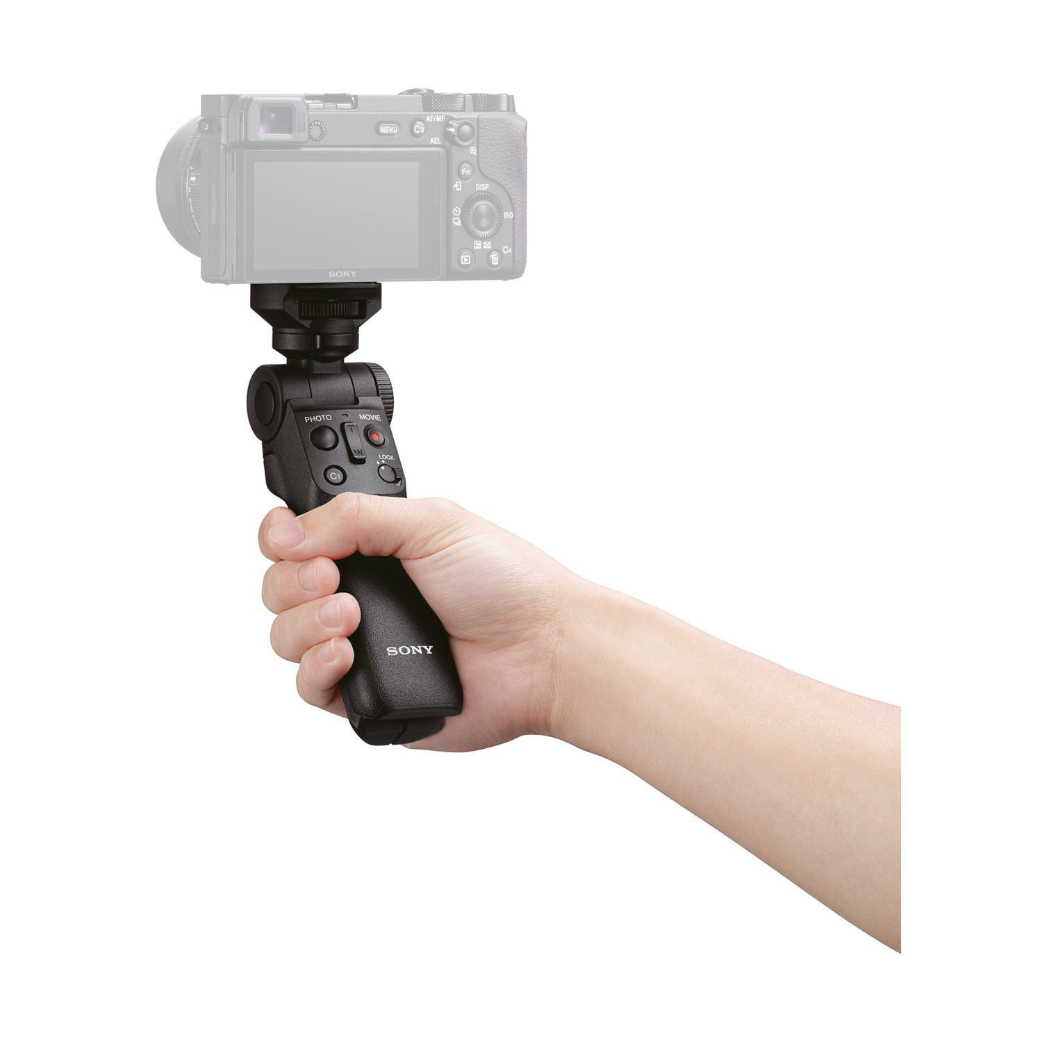 Mano che tiene un'impugnatura per fotocamera nera con pulsanti, collegata a una fotocamera grigia su sfondo bianco.