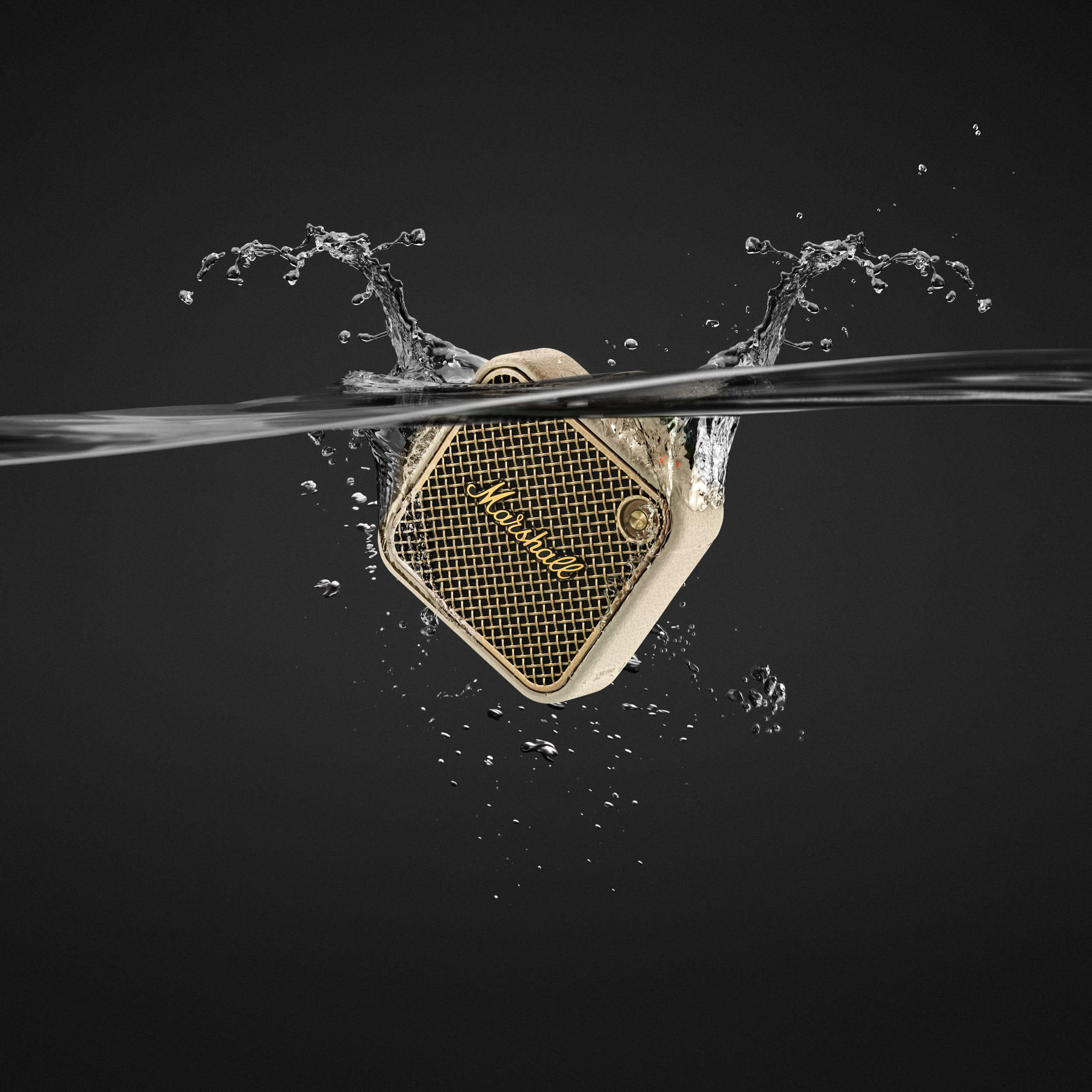 Ein beiger Marshall-Lautsprecher im Wasser. Wasserspritzer. Schwarzer Hintergrund.