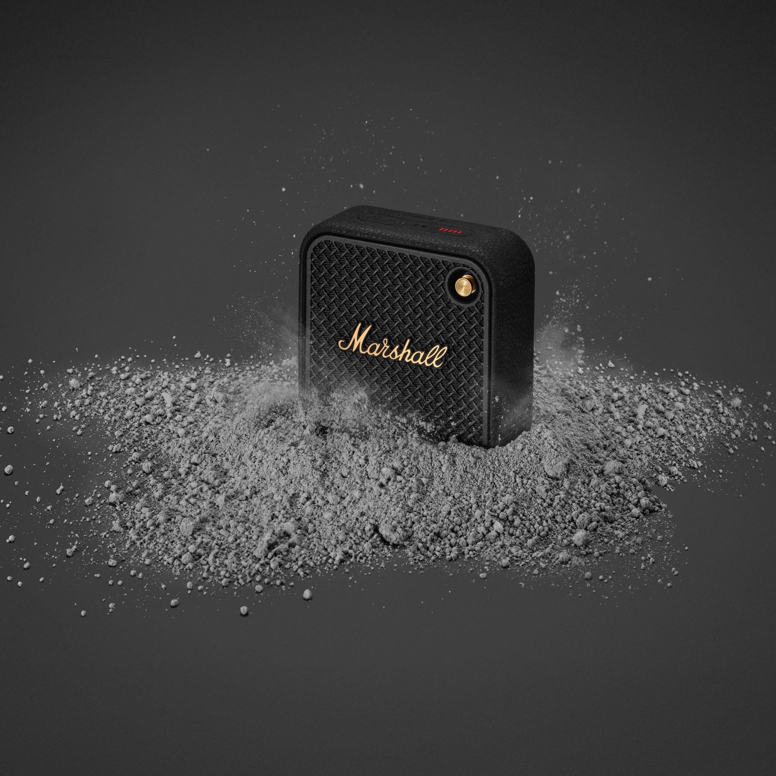 Ein schwarzer Marshall-Lautsprecher auf einer grauen Oberfläche mit Staub.