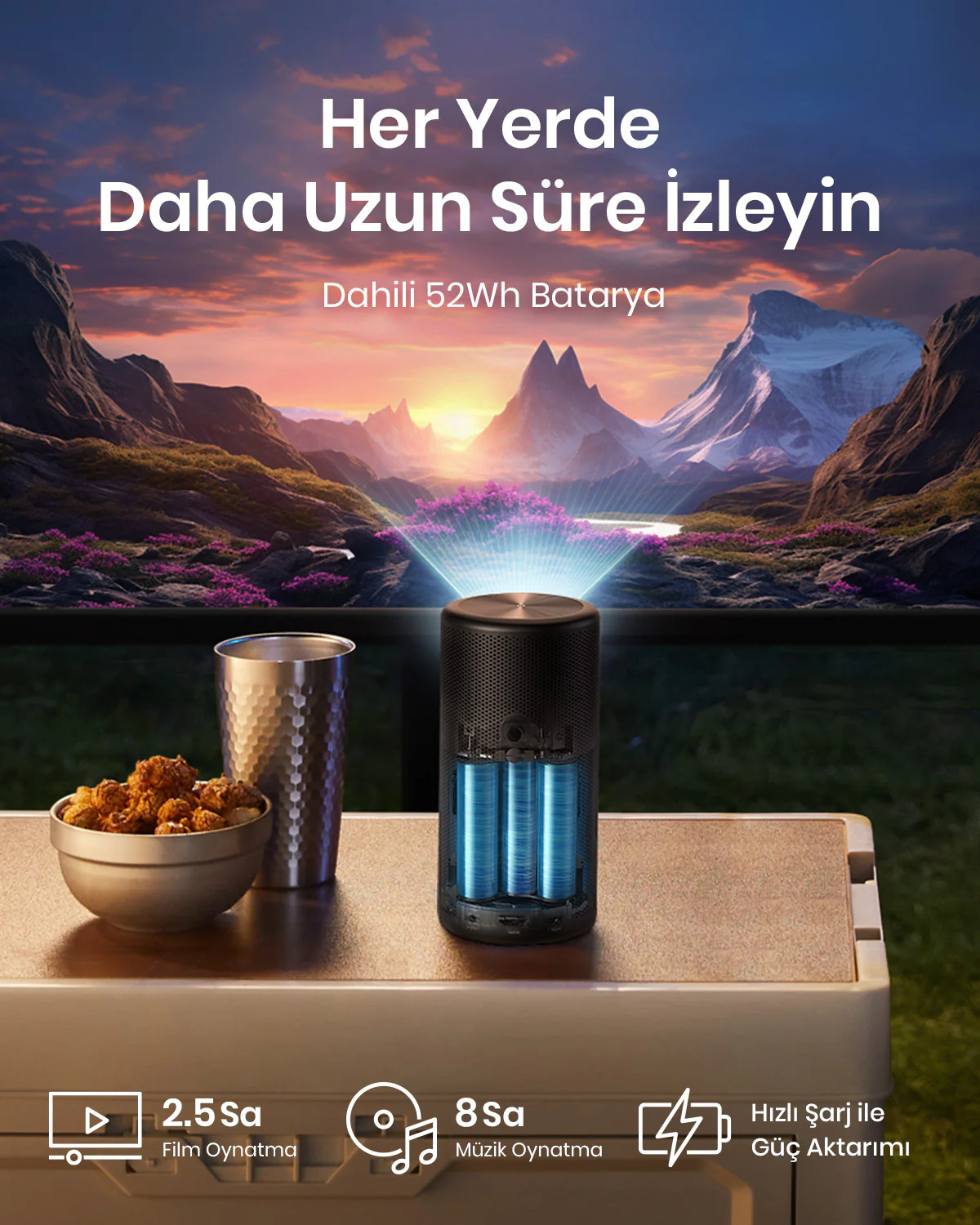 Bir masanın üzerinde atıştırmalıklar ve bir bardak ile bir hoparlör, dağ manzarası.