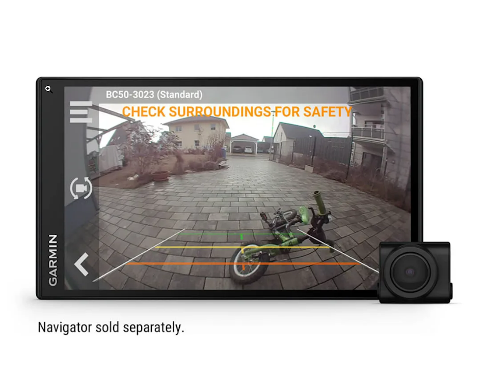 Deska rozdzielcza samochodu z ekranem wyświetlającym widok z kamery i tekst: 'CHECK SURROUNDINGS-FOR SAFETY'.