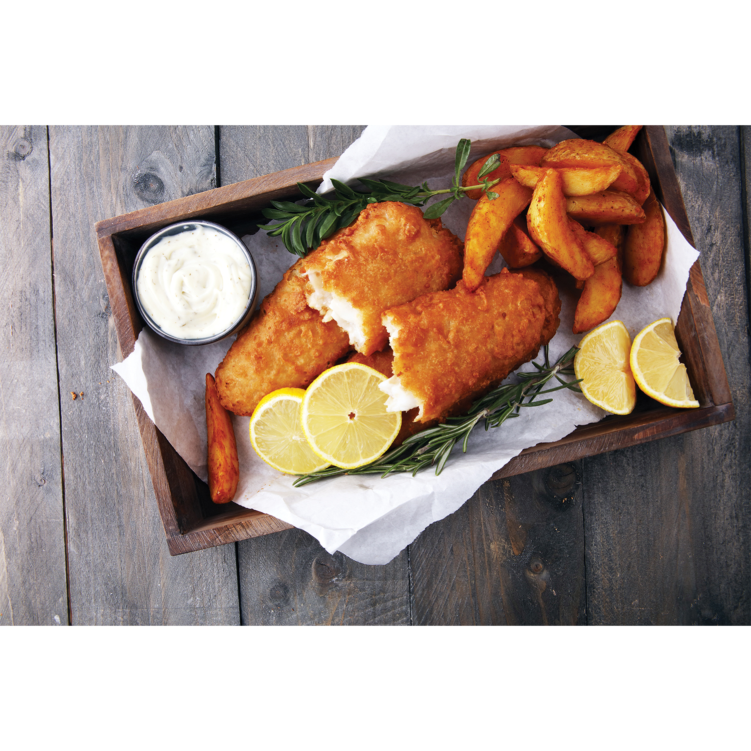 Fish and chips con fettine di limone e salsa tartara su un vassoio di legno, rustico.