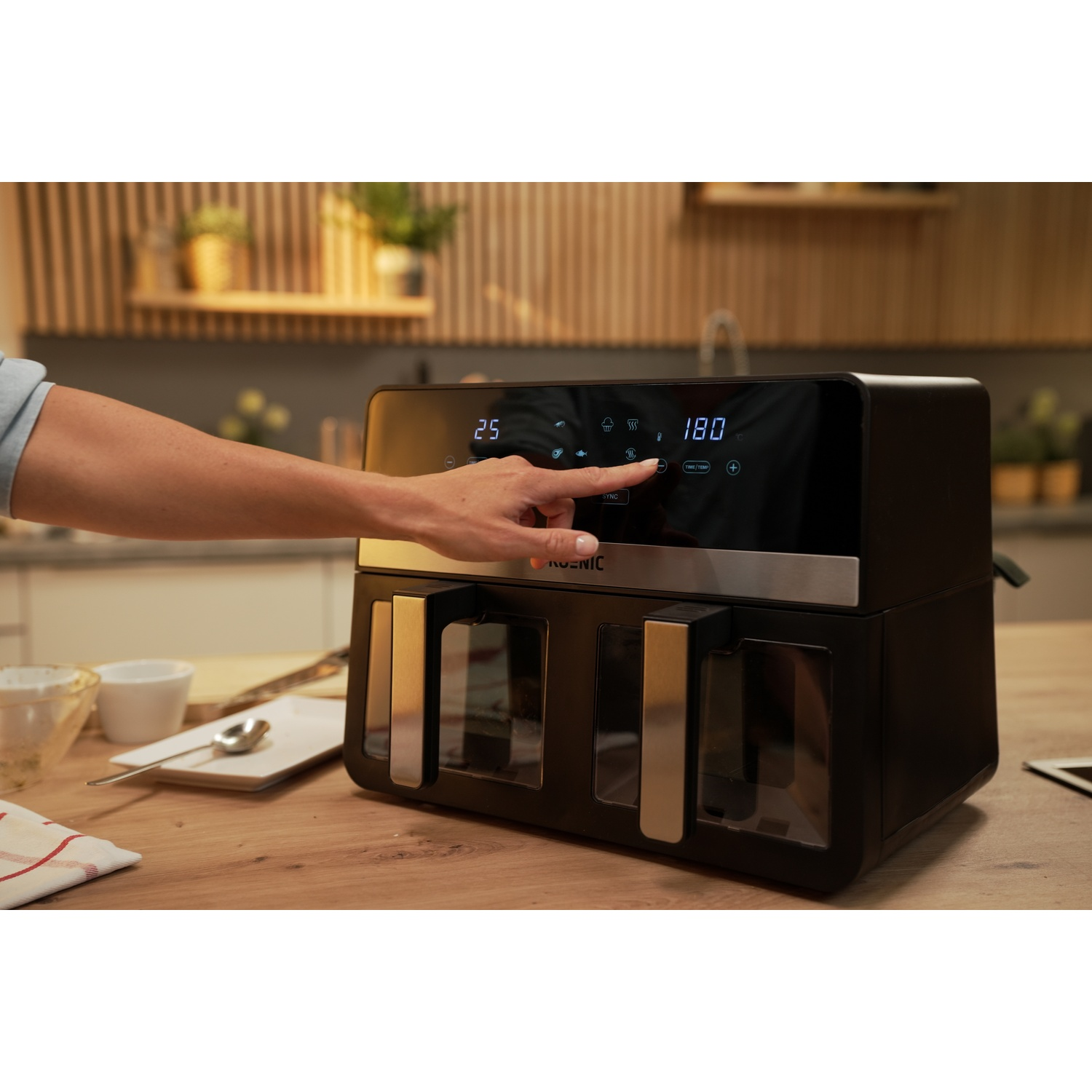 Una friggitrice ad aria con la mano di una persona che tocca il display. Il display mostra numeri.