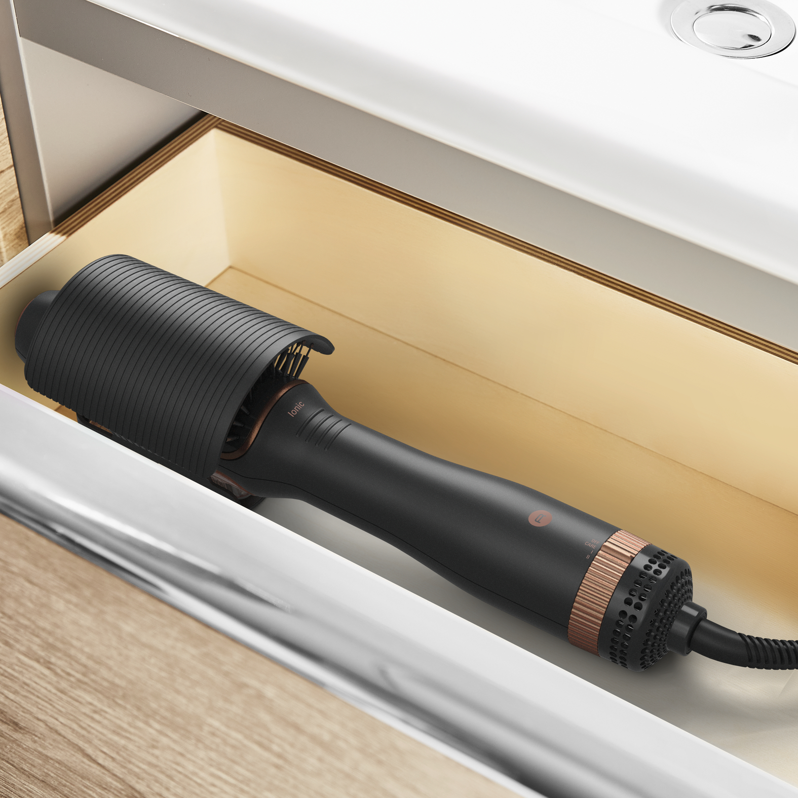 Cepillo de peinado negro y oro rosa dentro de un cajón con interior de madera.