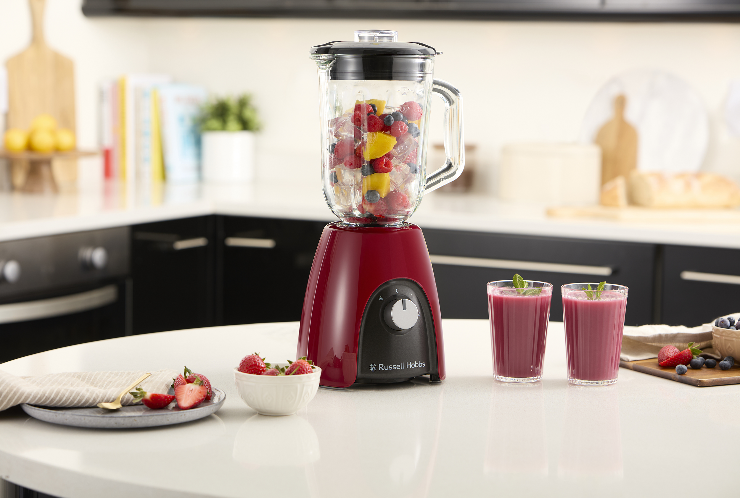 Turmixgép gyümölccsel, két smoothie-s pohár az asztalon. Friss eper, áfonya és citrom található.