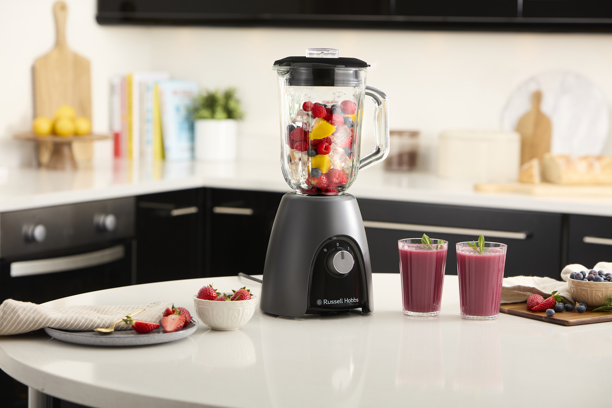 Turmixgép gyümölccsel, két smoothie-val. Eper és egy tál bogyó.