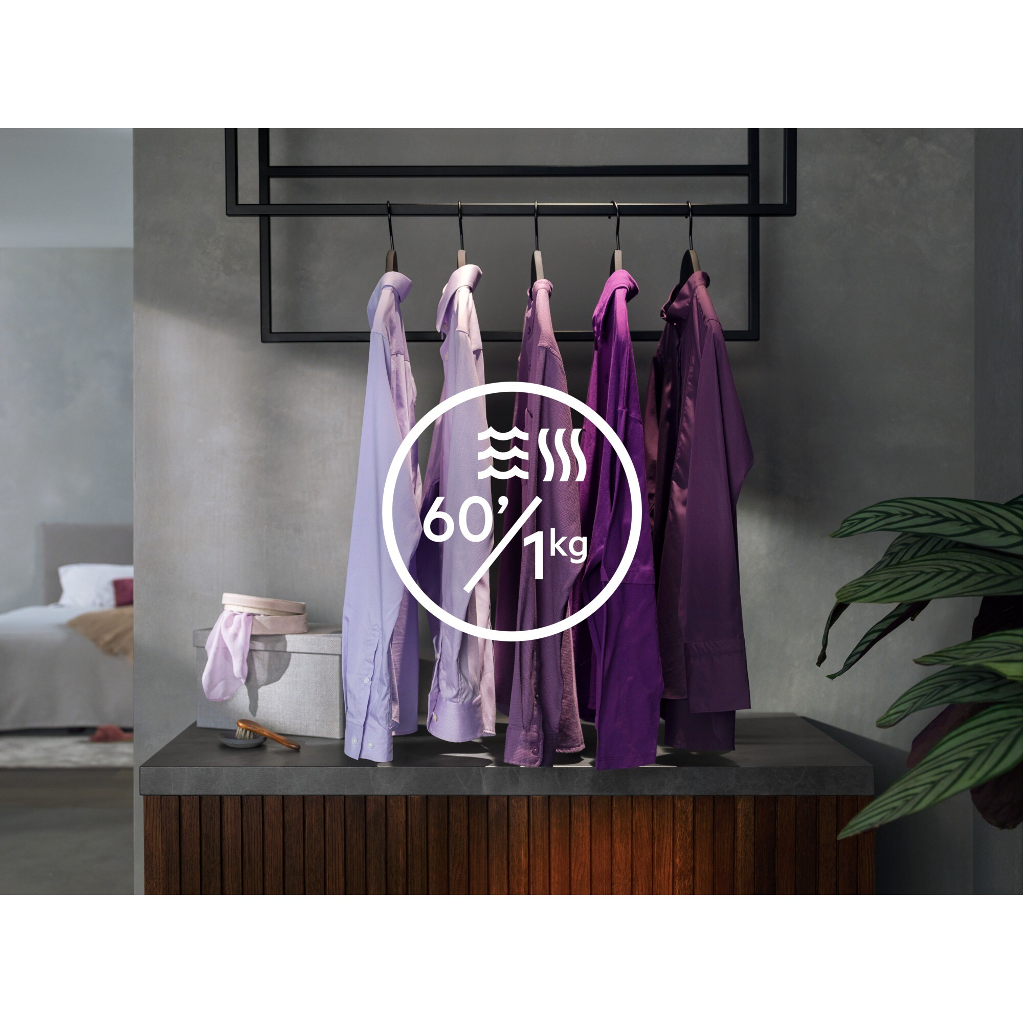 Ropa colgando de una rejilla con un gráfico circular que indica 60 minutos y 1 kg. Un dormitorio en el fondo.