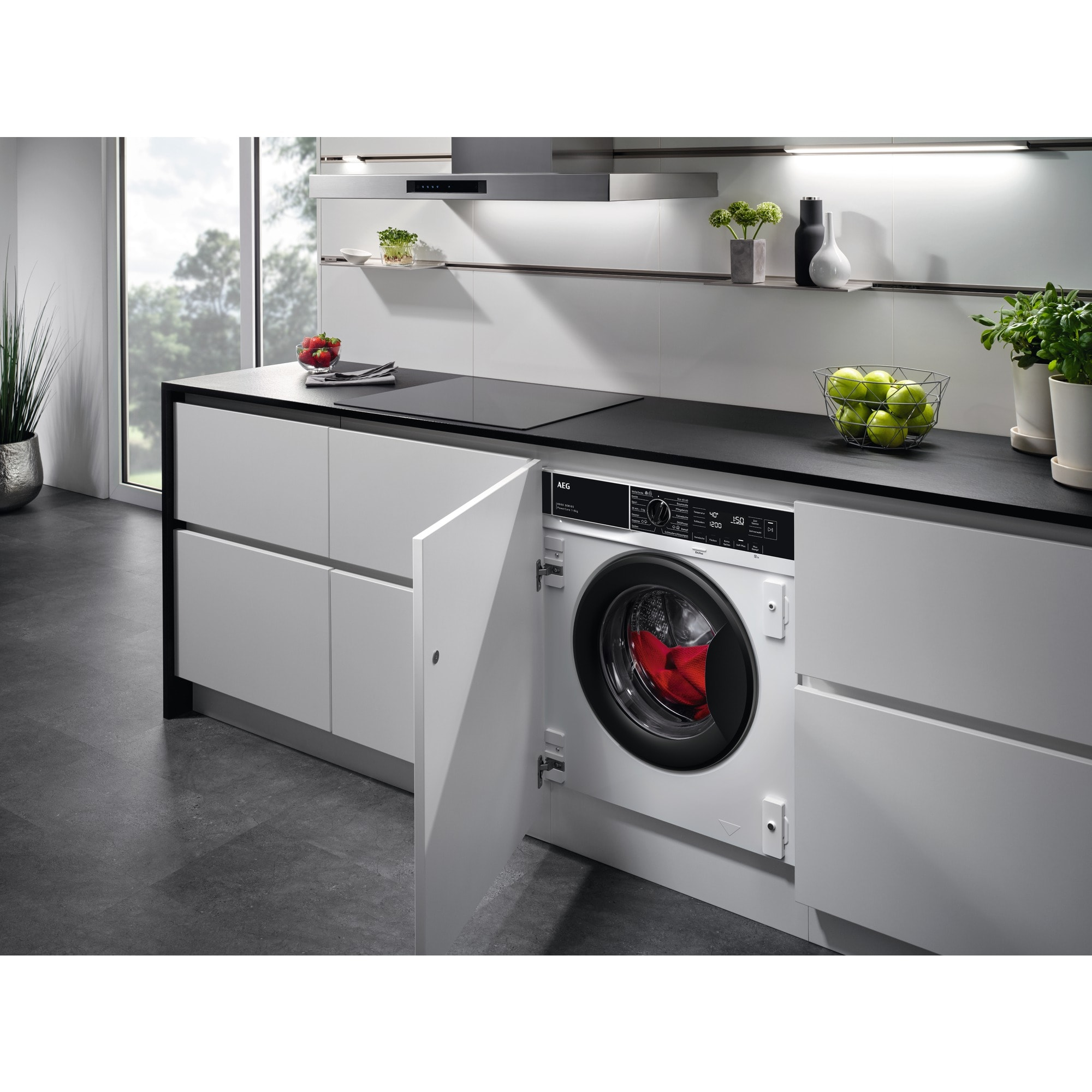 Una cocina moderna con una lavadora blanca empotrada. Una puerta abierta revela el tambor rojo.
