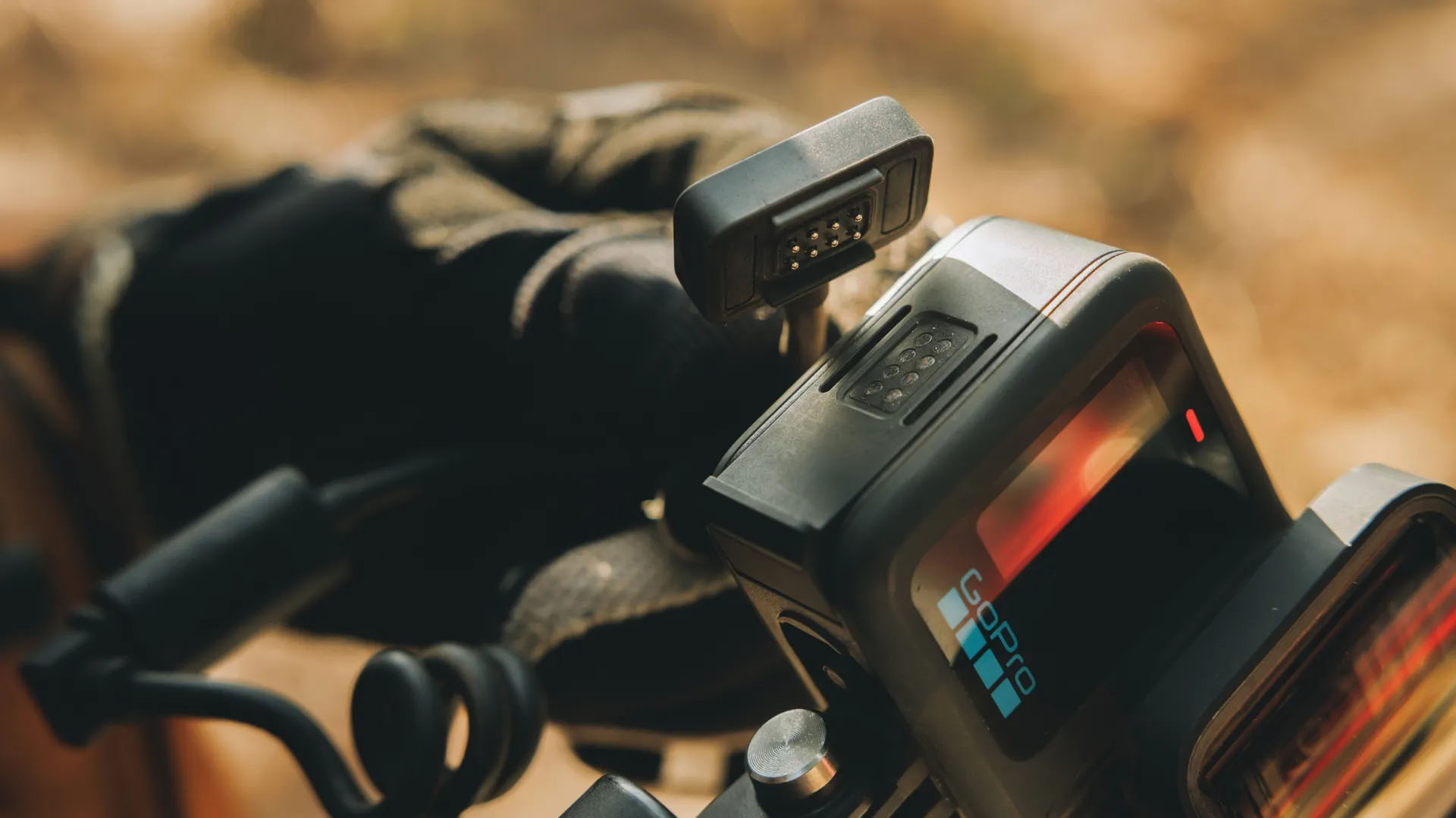 Karanlık yüzeye monte edilmiş GoPro kameranın yakından görünümü, siyah eldivenli el.