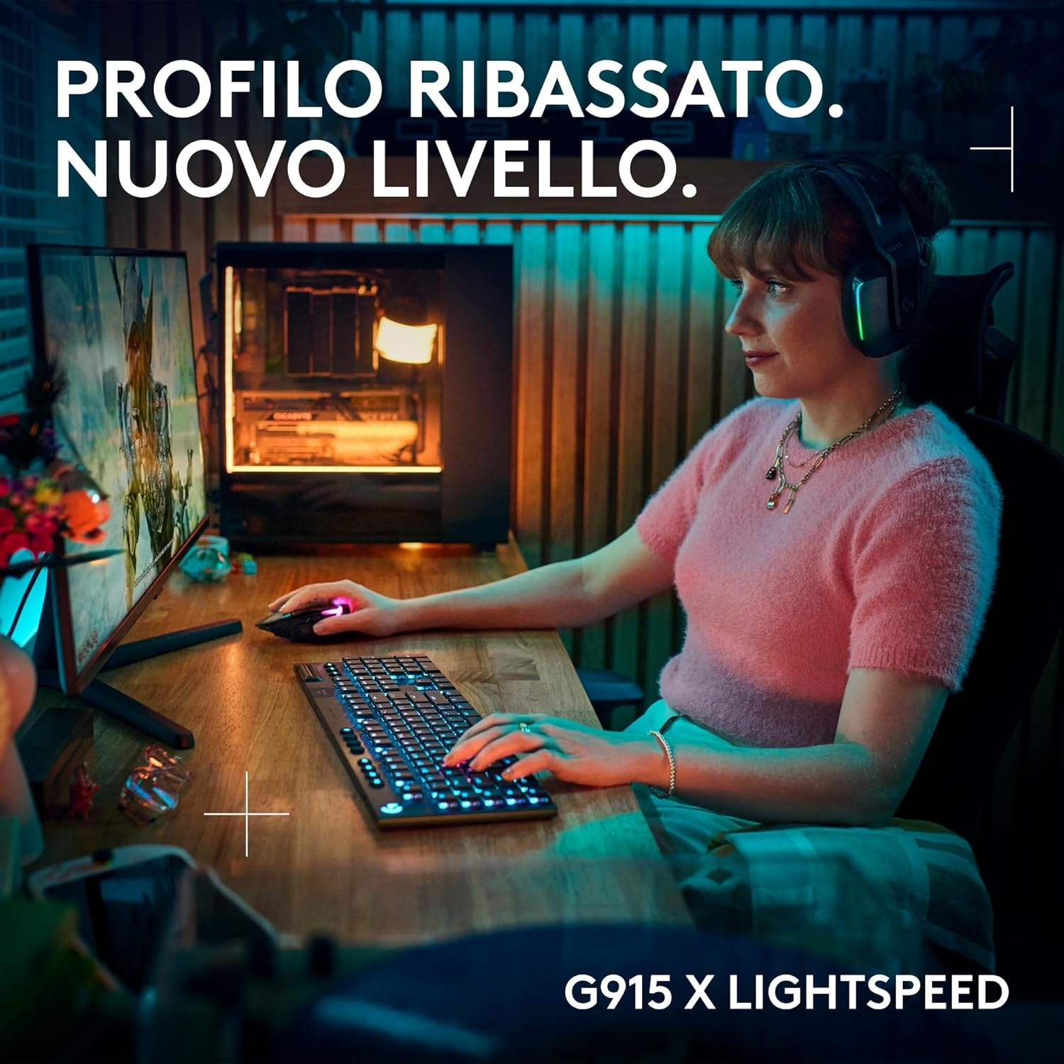 Donna con cuffie e tastiera, configurazione gaming. Camicia rosa, capelli scuri, computer sulla scrivania.
