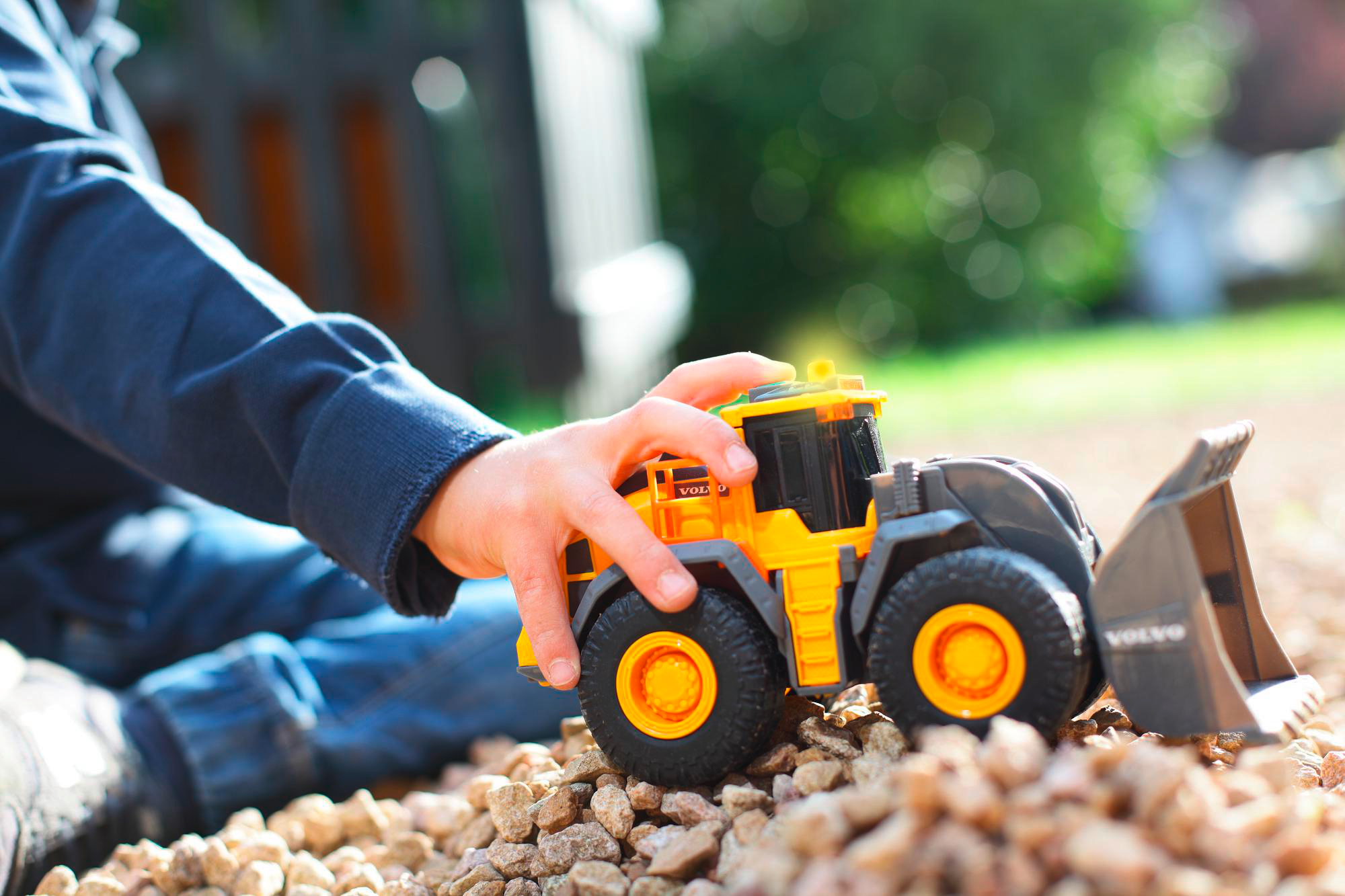 Kinderhand spielt mit einem orange-grauen Spielzeug-Baufahrzeug.