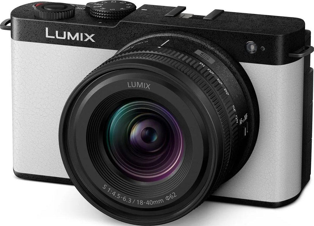 Un appareil photo Lumix noir et blanc. L'objectif est proéminent, avec le logo Lumix visible. L'appareil photo a un corps argenté et un dessus noir.