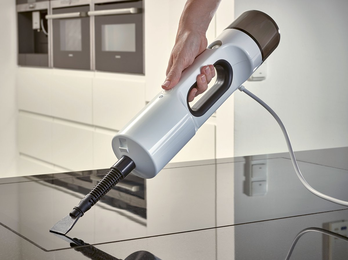 Ręka osoby używającej białej parownicy na czarnej powierzchni.