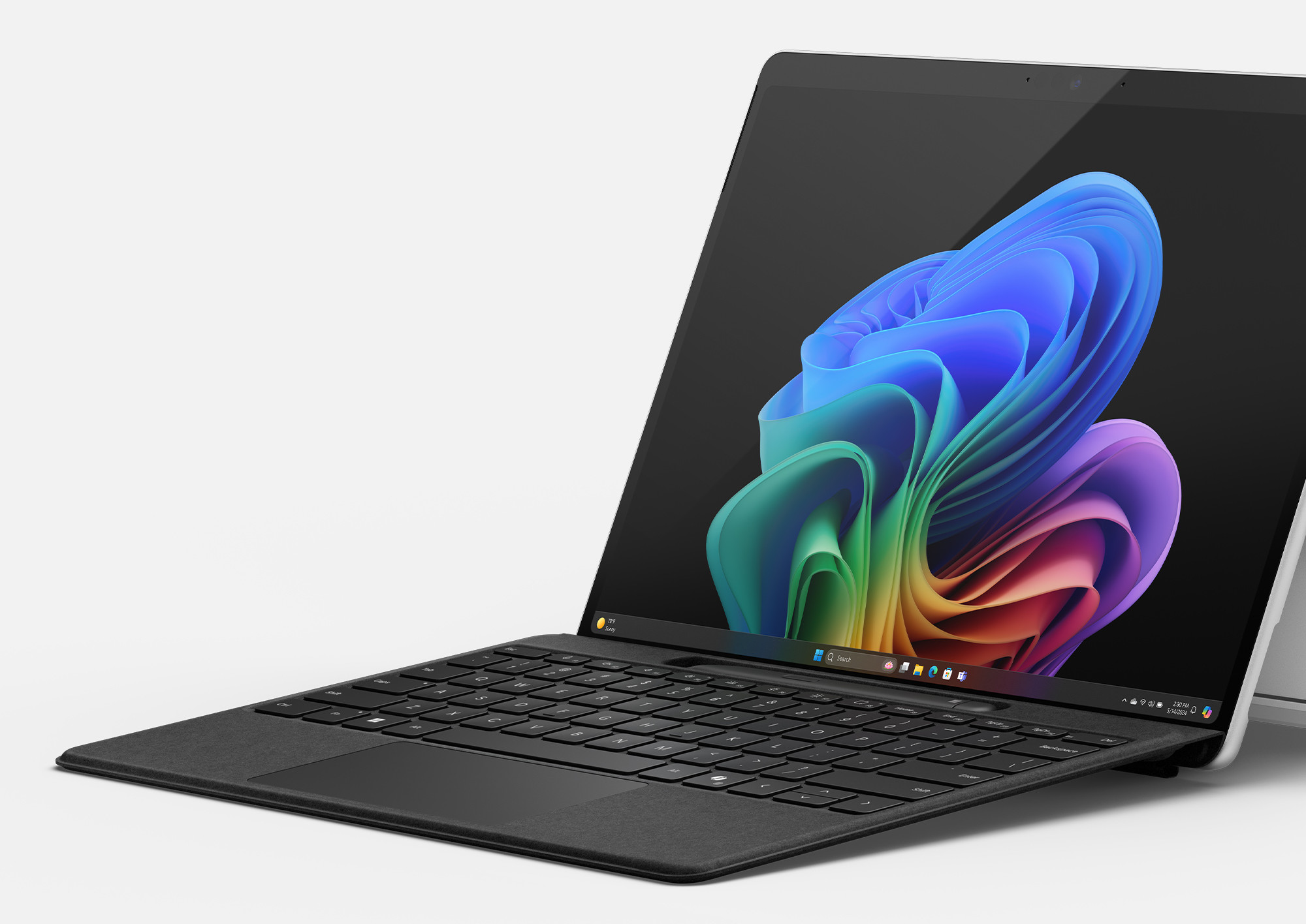 Laptop z czarną klawiaturą, ekran wyświetlający kolorową sztukę abstrakcyjną. Leży na białej powierzchni.