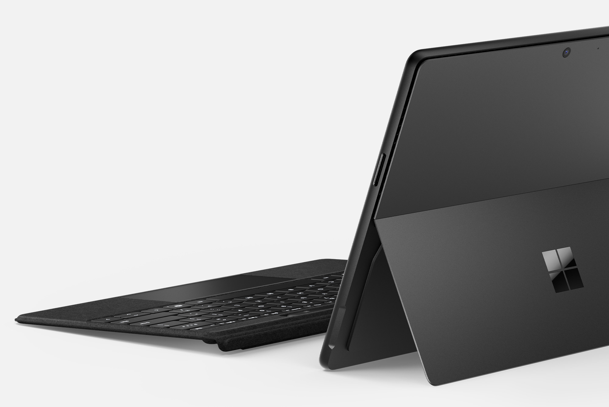 Czarny Microsoft Surface z dołączoną klawiaturą. Urządzenie jest otwarte. Widoczne jest logo Microsoft.