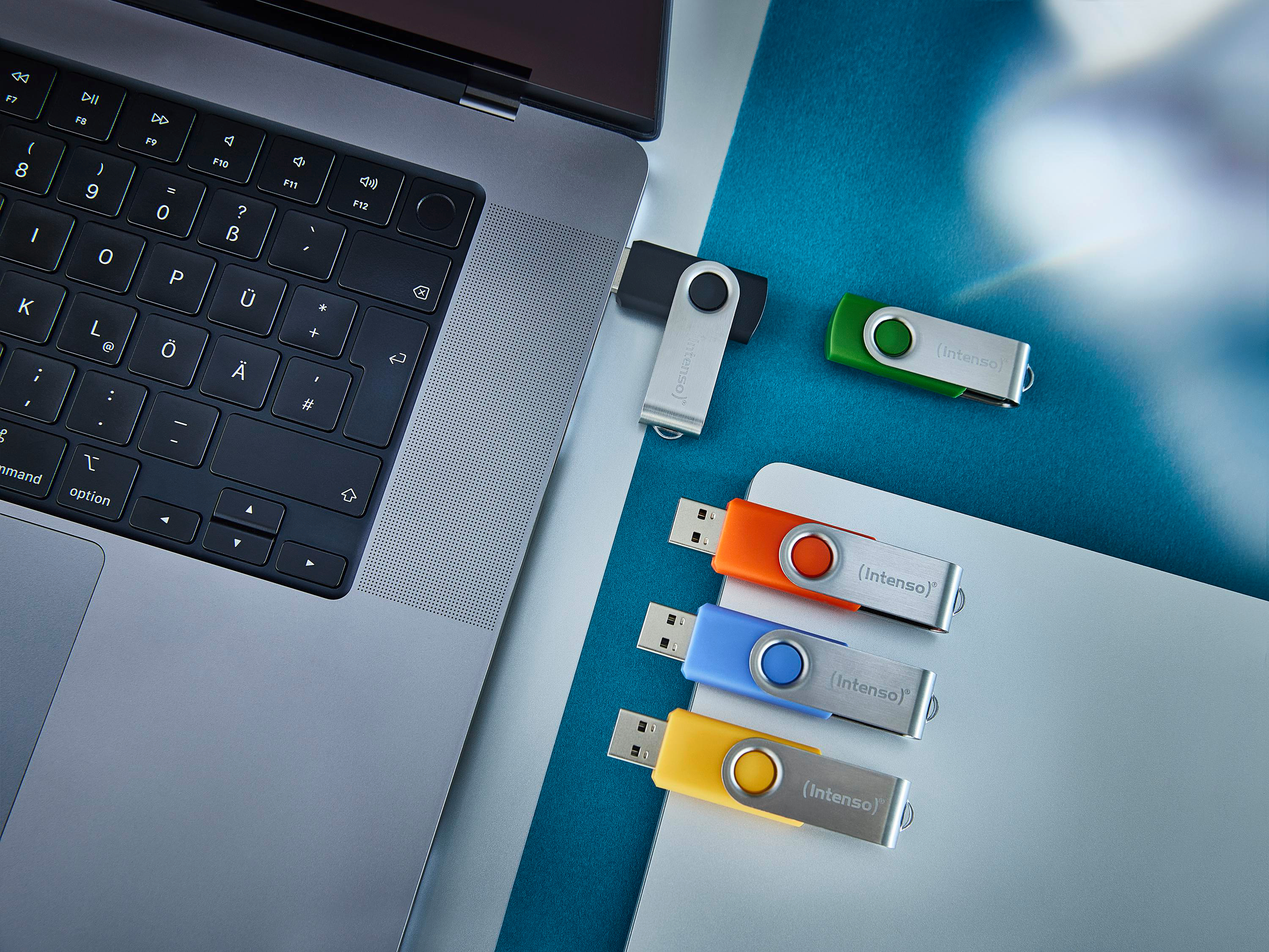 Ein Laptop mit bunten USB-Laufwerken auf einer blauen Oberfläche.