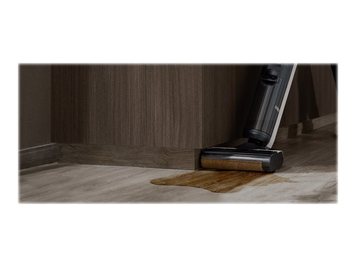 Ein Staubsauger reinigt eine braune Flüssigkeit auf einem hellen Holzboden.