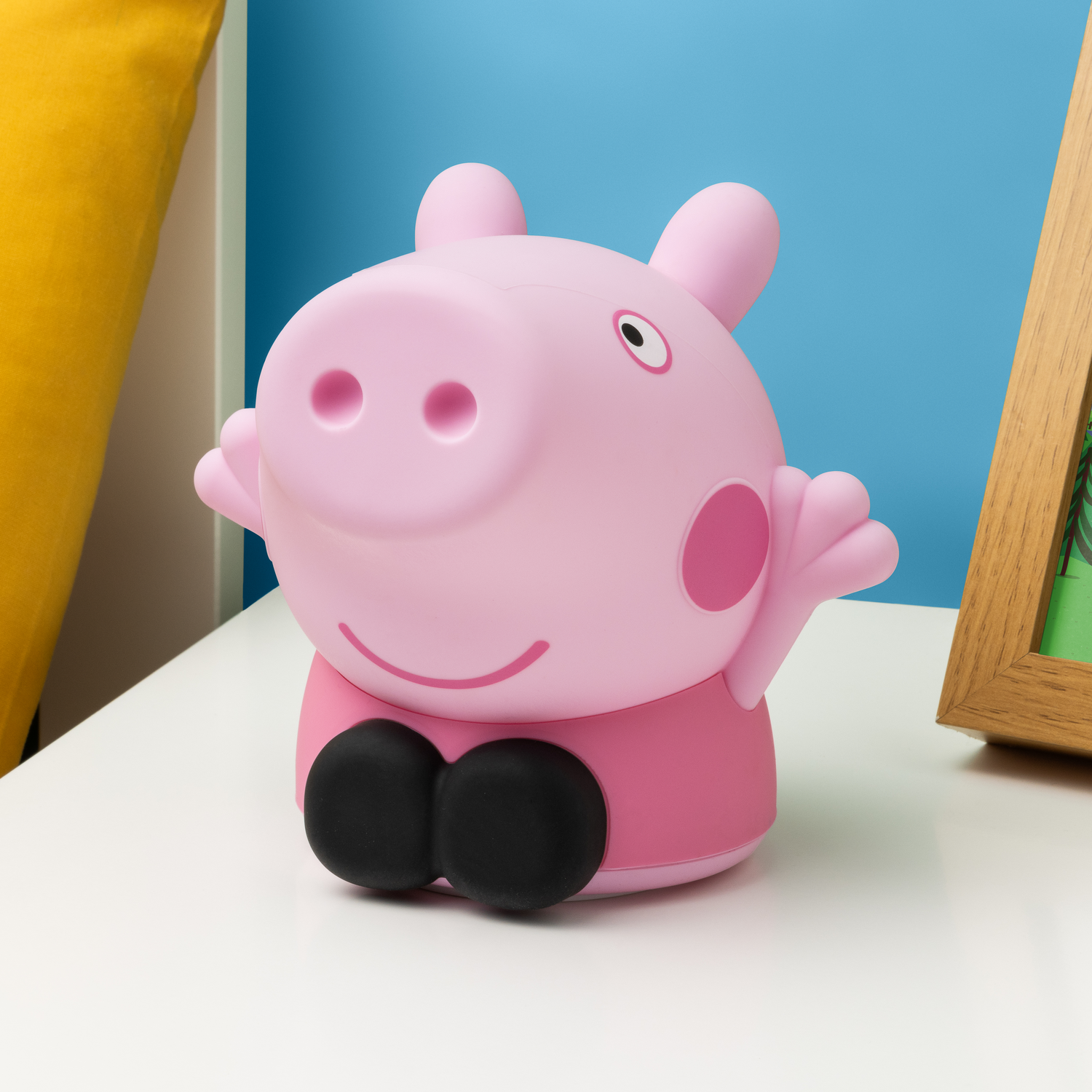 Pink Peppa Pig toy. Black feet and a pink top. Sitting on a white surface.