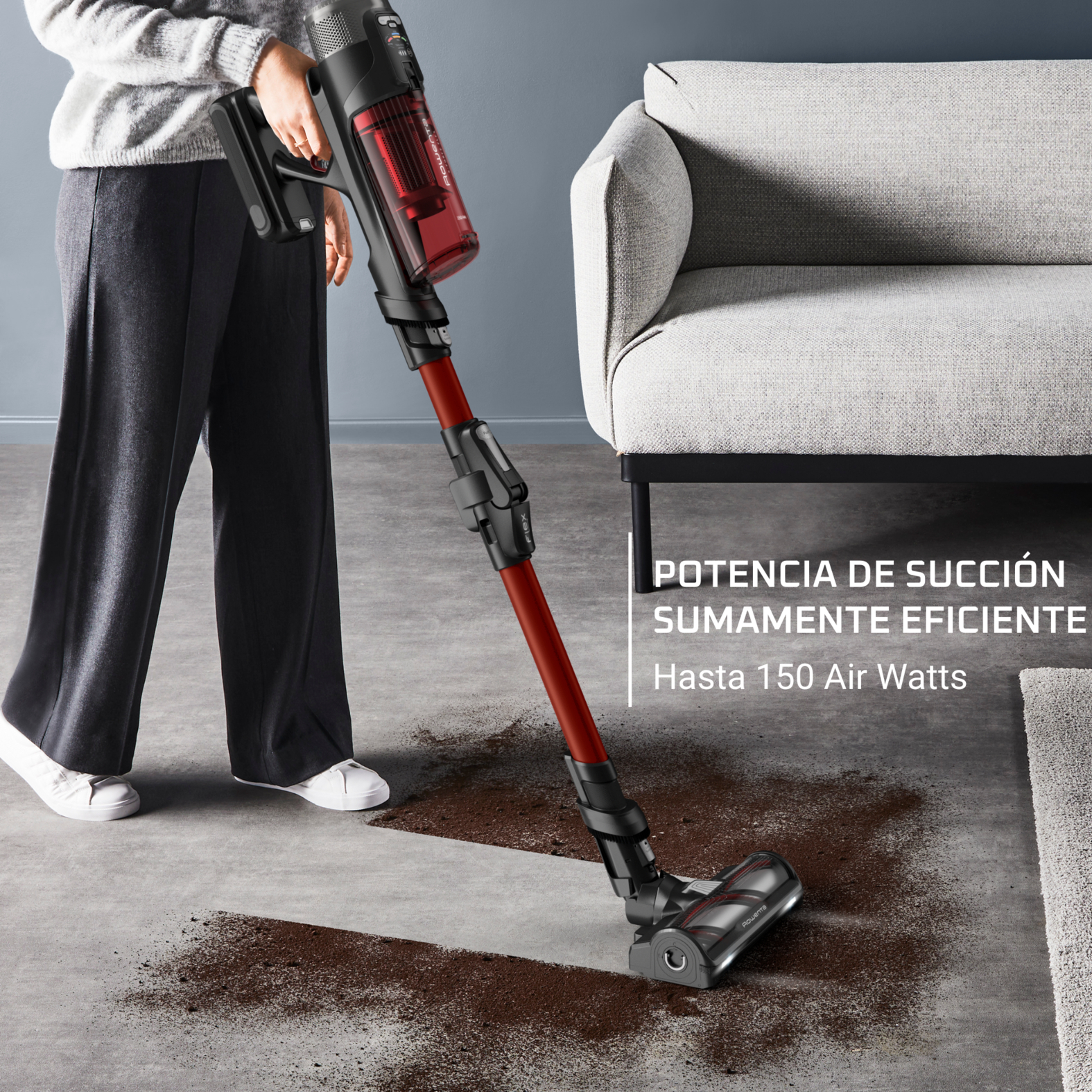 Una persona aspirando una alfombra con una aspiradora de mano roja y negra.