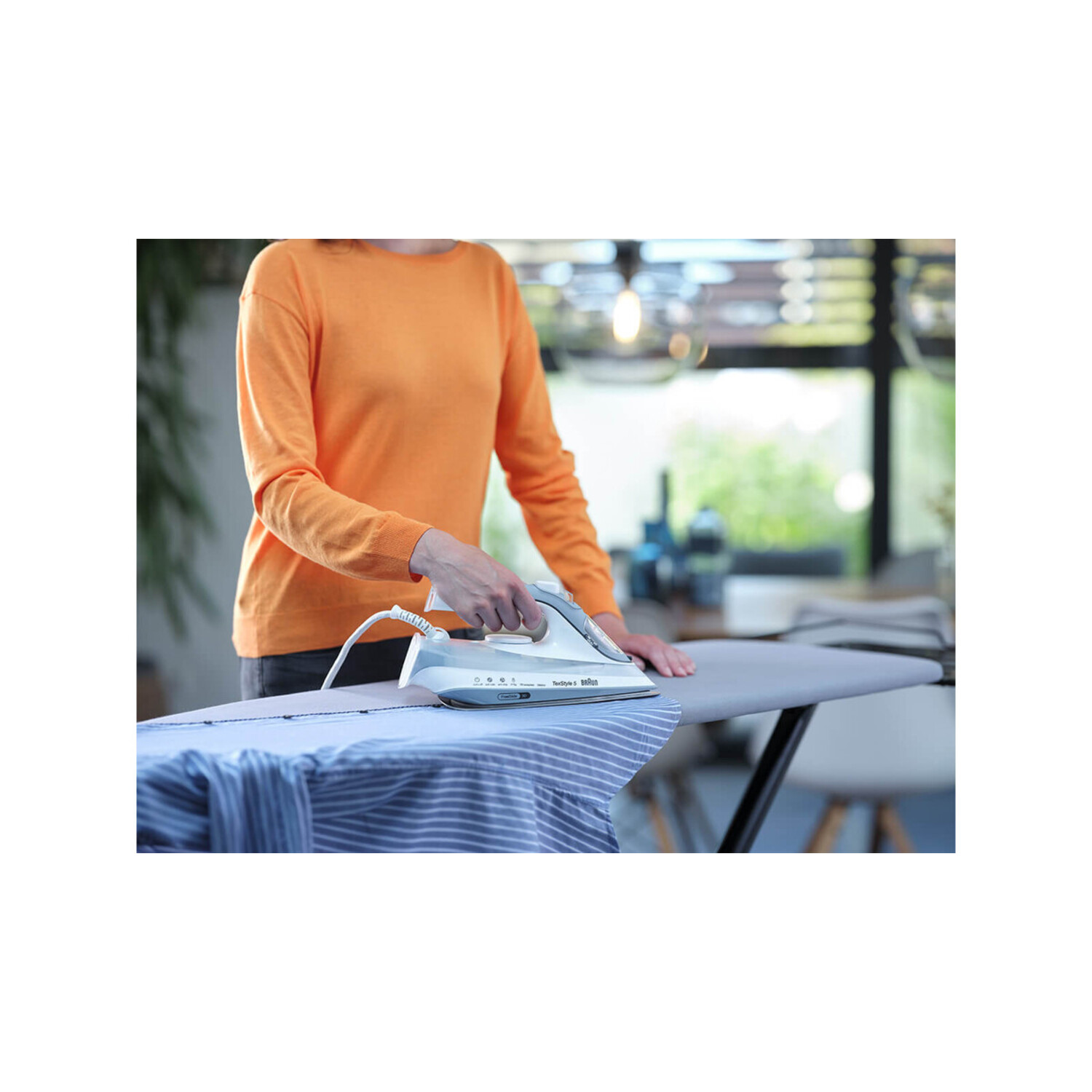 Personne repassant une chemise bleue sur une planche à repasser.