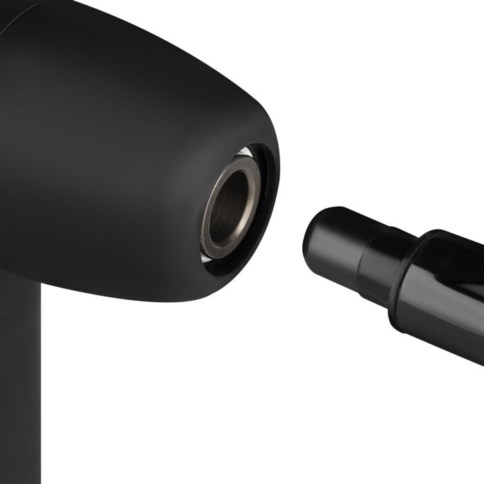 Zbliżenie czarnego obiektu z cylindrycznym otworem i odłączonym walcem, wszystko na białym tle.