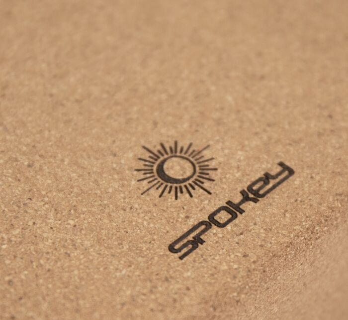 Zbliżenie na powierzchnię korka z logo słońca i napisem 'Spokey' w kolorze czarnym.