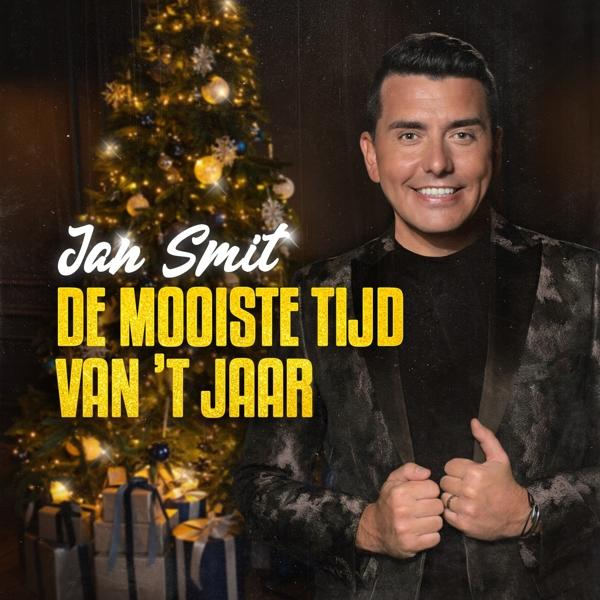 Pochette d'album avec un homme souriant devant un sapin, texte en jaune.