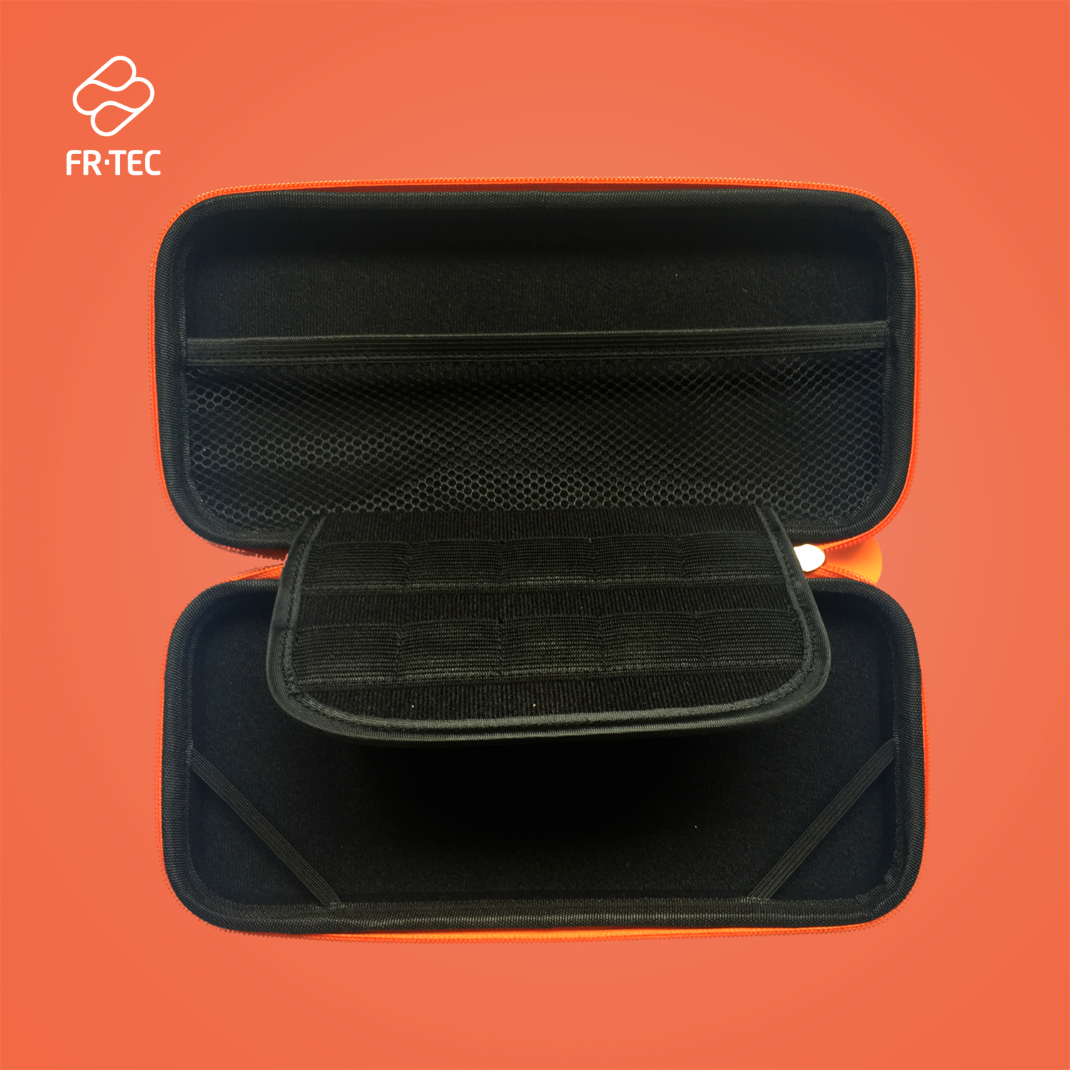 Geöffnete orangefarbene FR-TEC-Tragetasche. Innenraum hat schwarze Netztasche und zwei Fächer. Roter Hintergrund.
