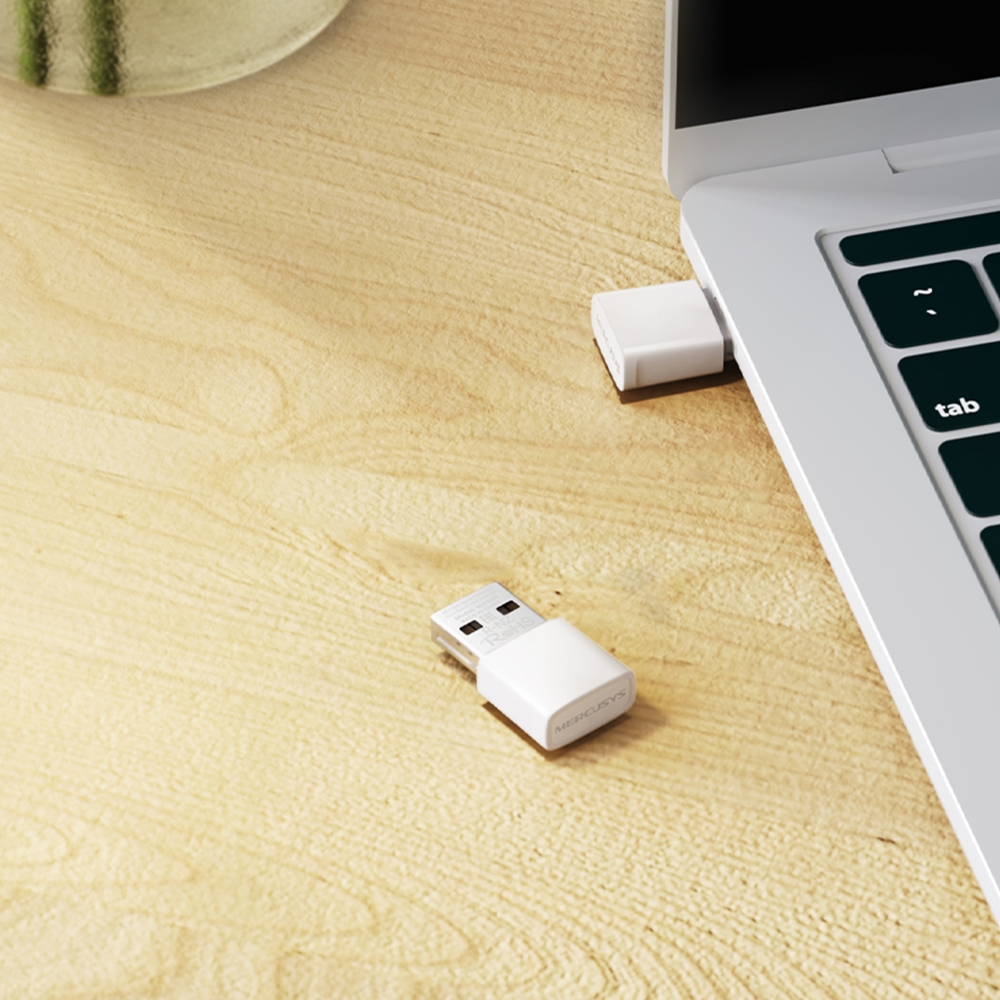 Biały adapter USB podłączony do laptopa na drewnianym biurku.