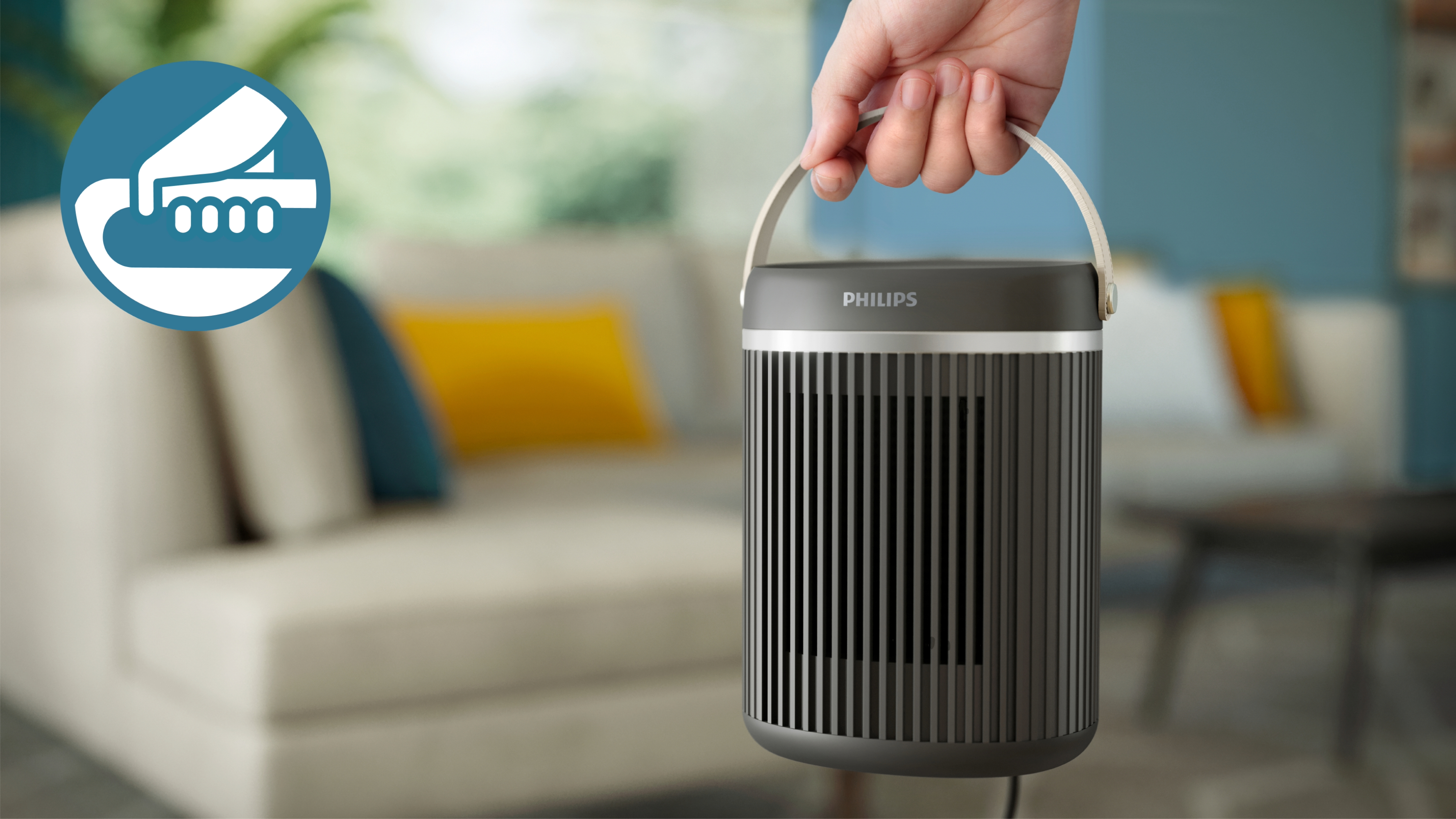 Una mano sosteniendo un calefactor Philips gris oscuro en un salón.