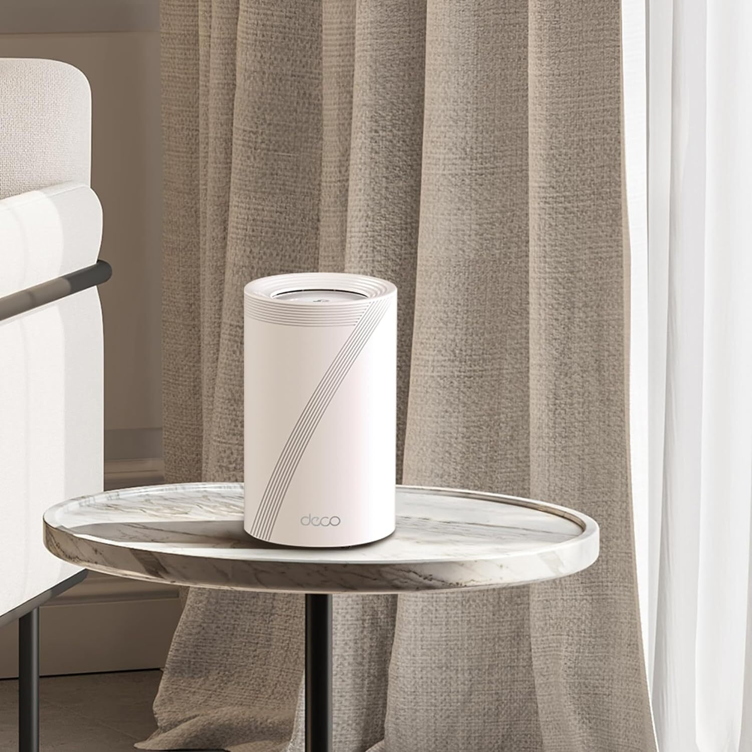 Appareil Deco cylindrique blanc sur une table en marbre, rideaux beiges en arrière-plan.