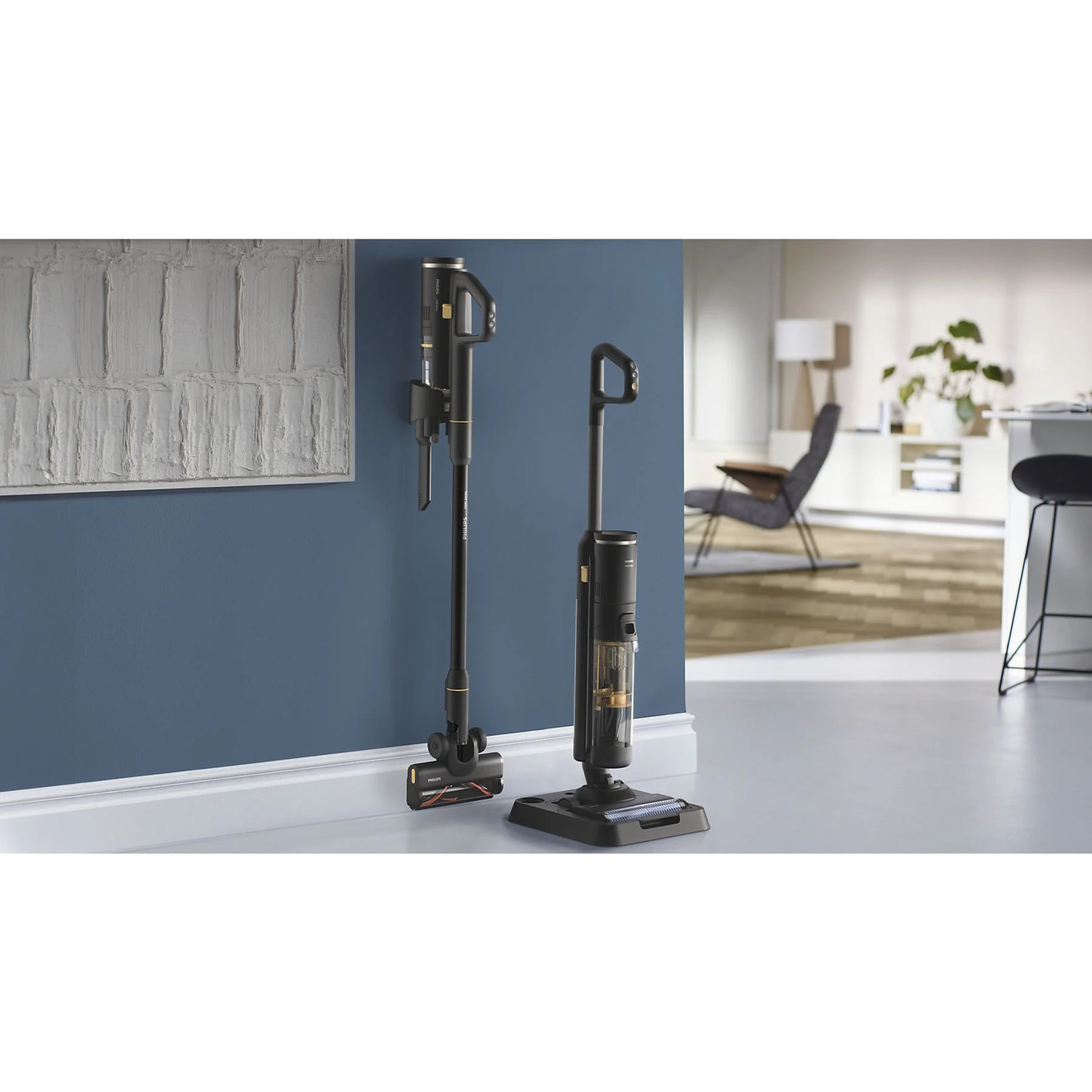 Two black and gold vacuum cleaners, one standing, one on the floor, in a room.