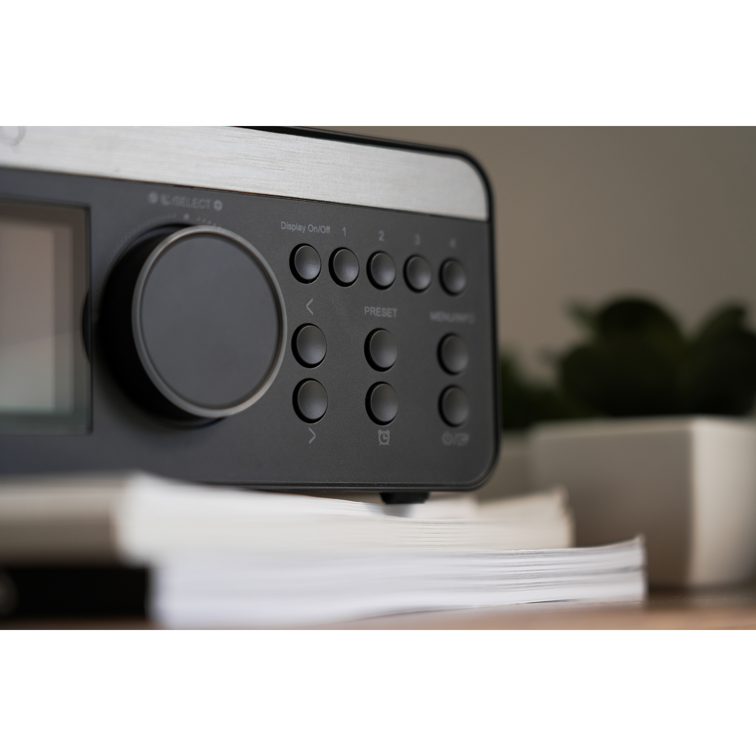 Primo piano di una radio nera con pulsanti e schermo, con libri vicini.