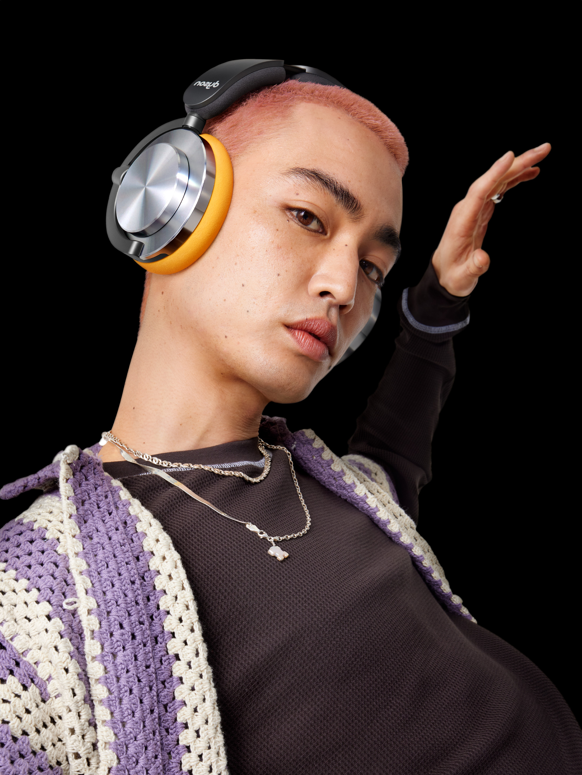Un hombre con auriculares y collar, con un fondo oscuro. Está mirando hacia adelante.