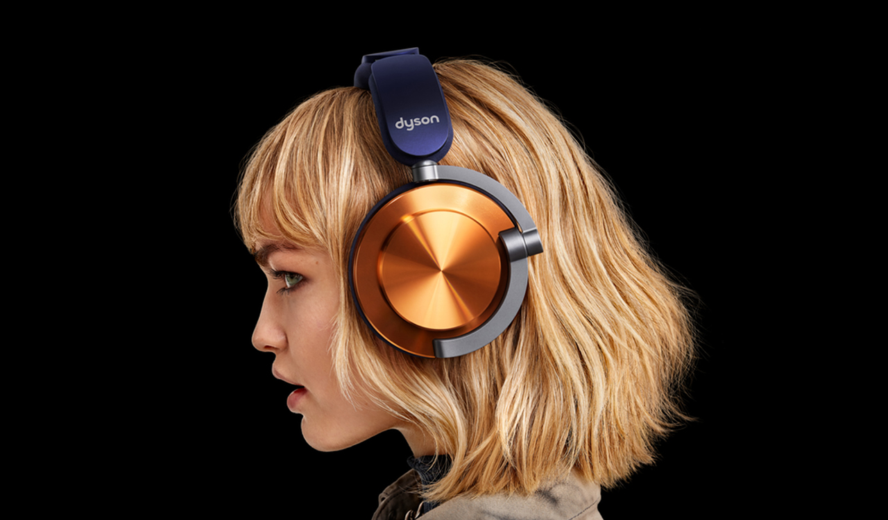 Una mujer con auriculares dorados y azules sobre fondo negro.