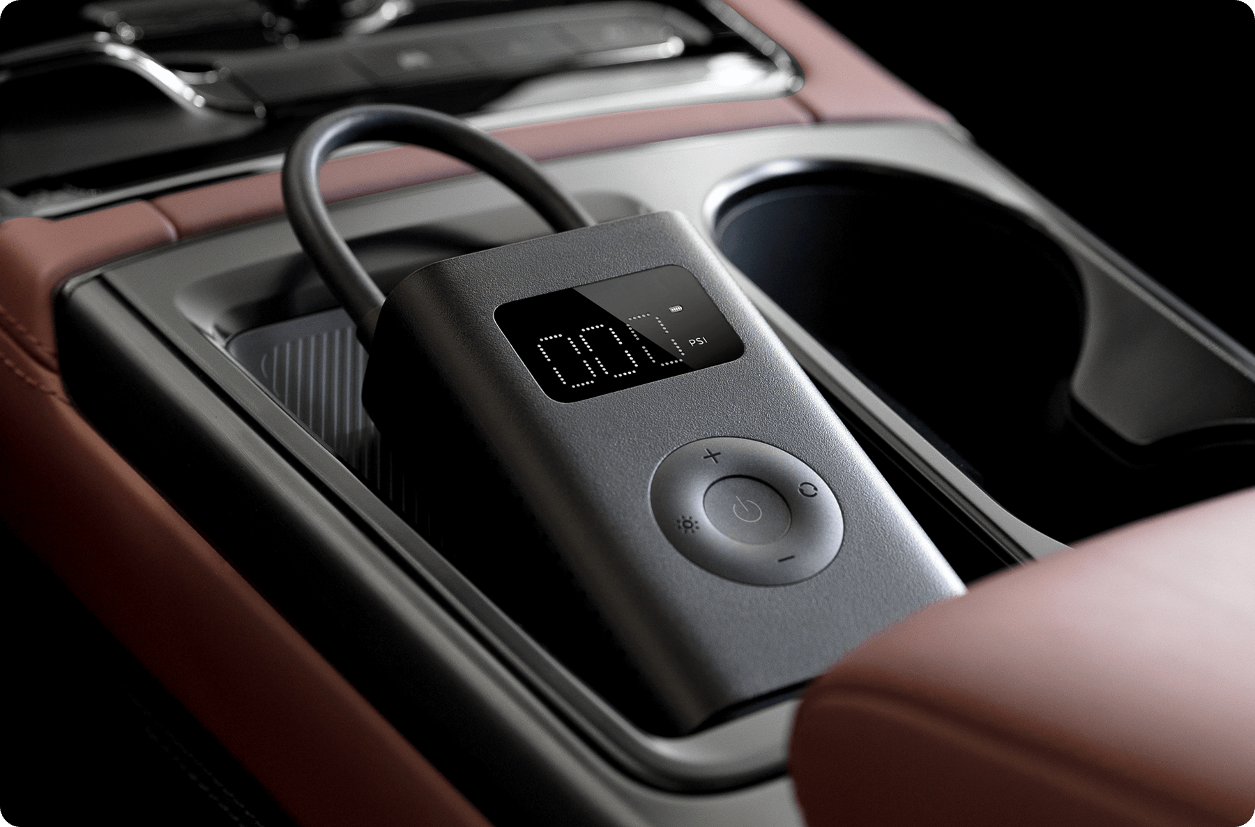 Una pompa d'aria portatile nera con display digitale è posizionata nella console centrale di un'auto.