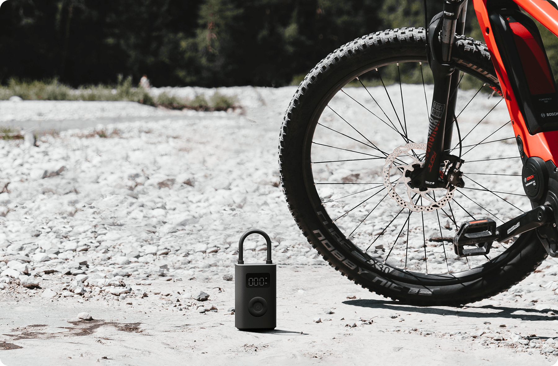 Pompa ad aria nera a terra vicino a una mountain bike. Fogliame verde sullo sfondo.