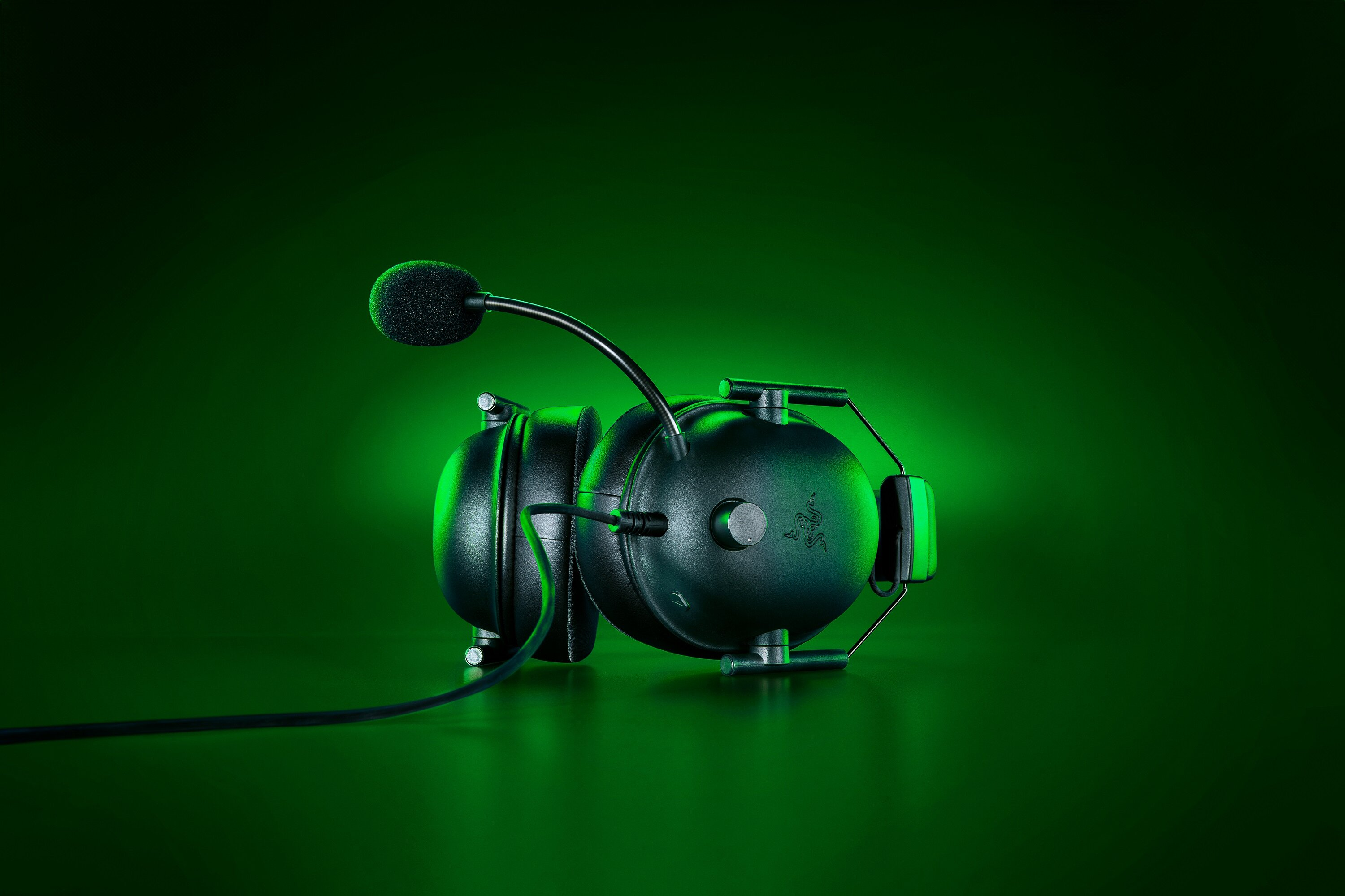 Czarny zestaw słuchawkowy Razer z mikrofonem na zielonym tle, widok pod kątem.