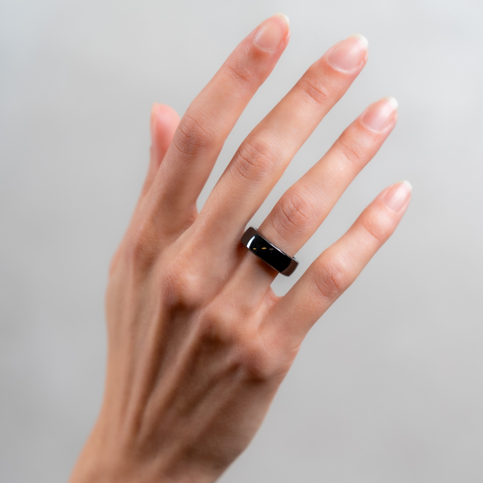 Die Hand einer Person, die einen schwarzen, rechteckigen Smartring trägt.