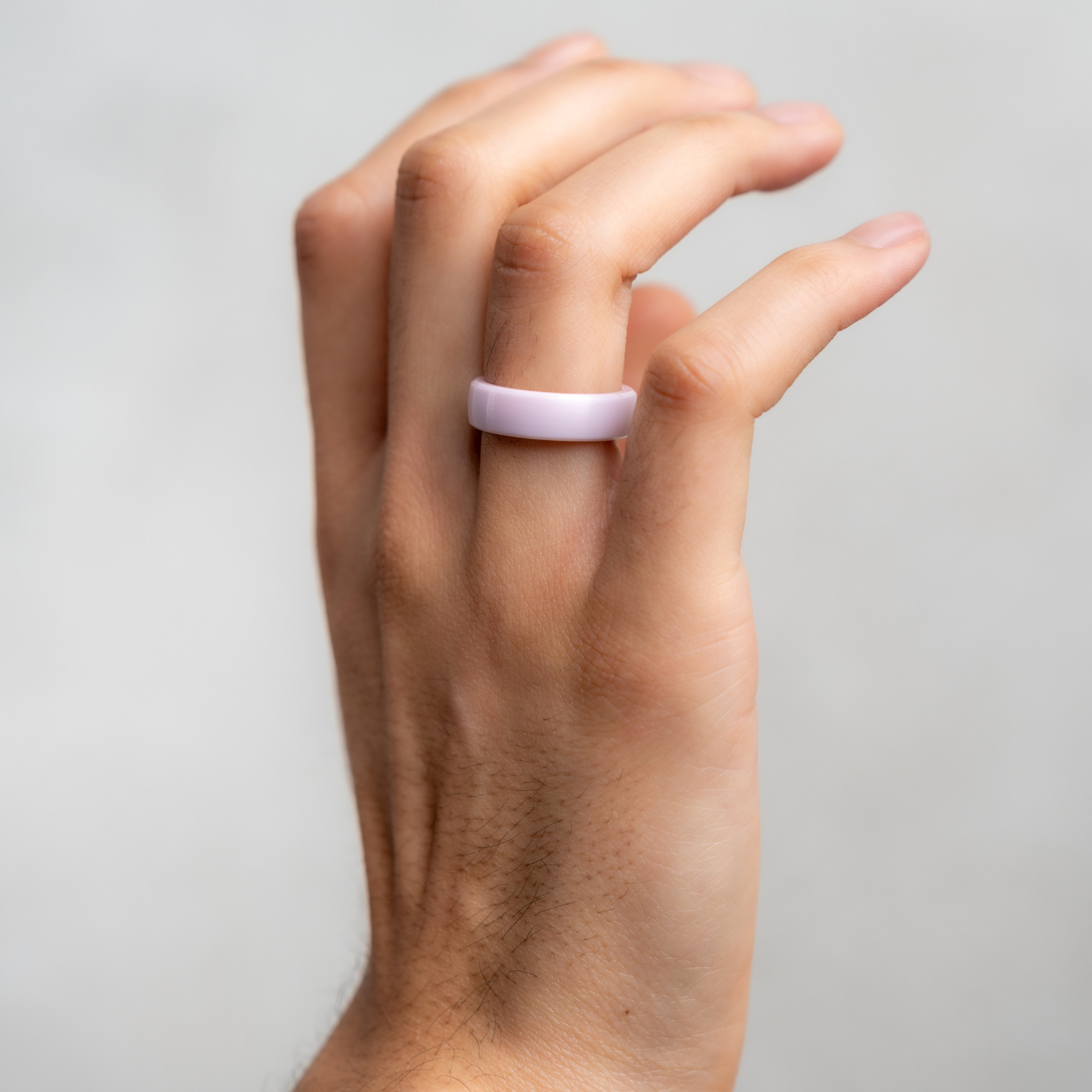 Eine Hand, die einen hellvioletten Ring trägt.