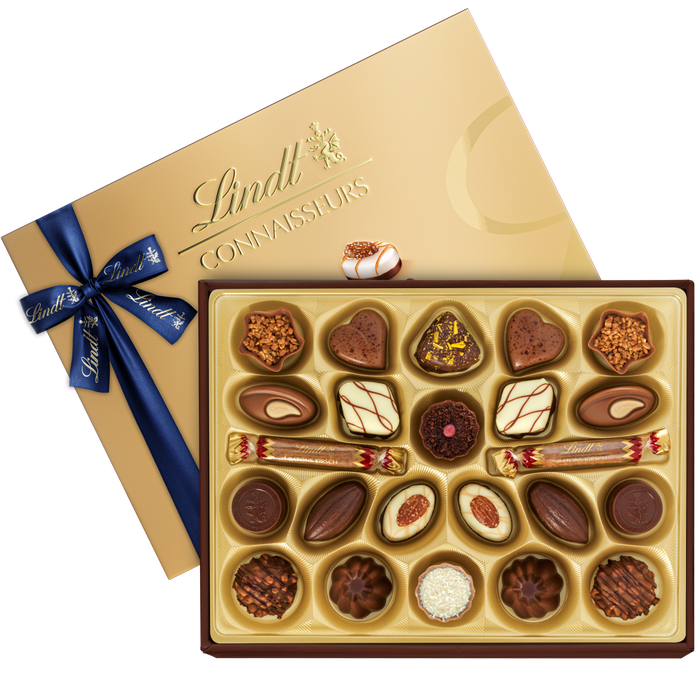 Una scatola dorata contenente cioccolatini Lindt di varie forme, con un nastro blu.