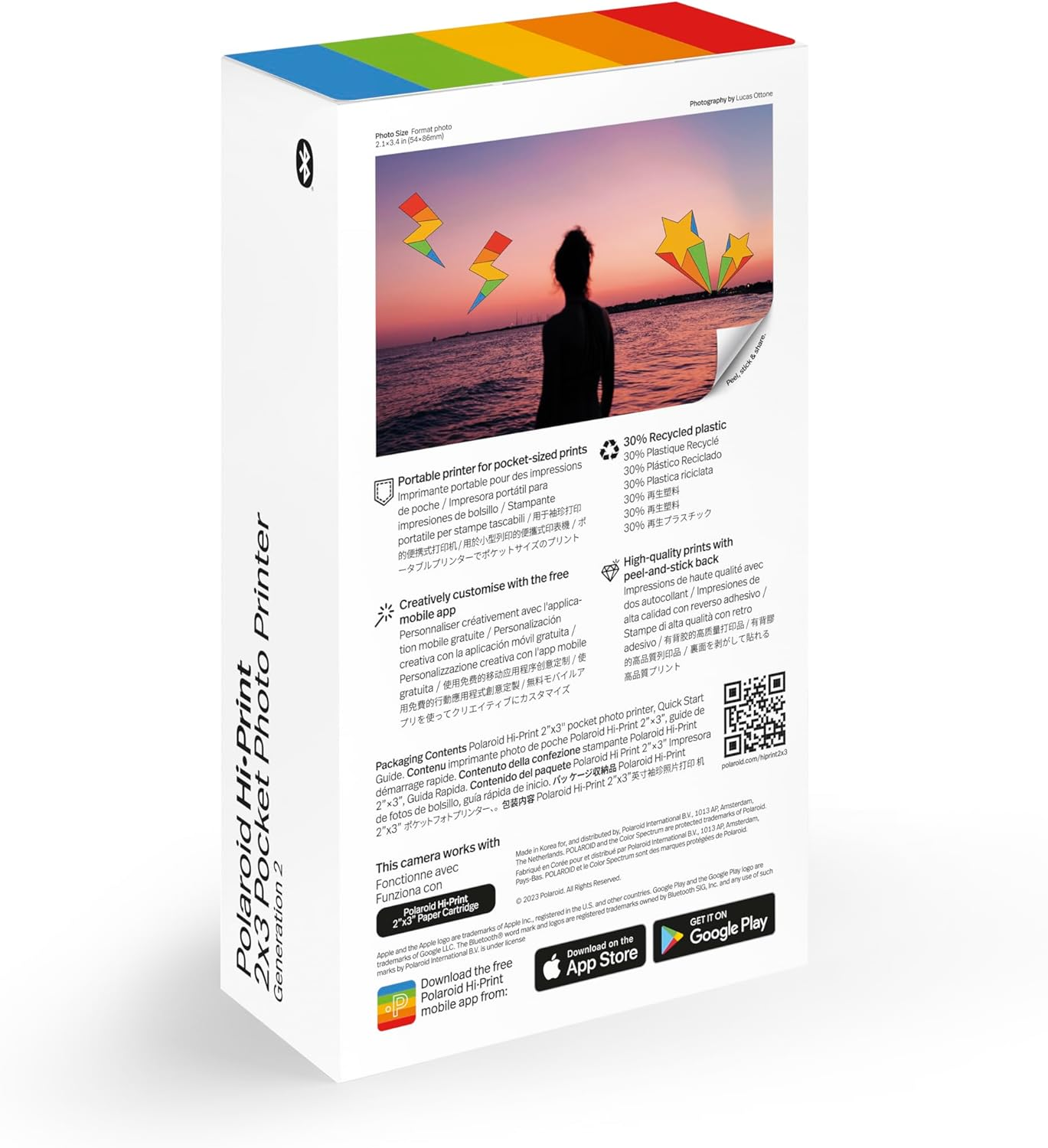 Caja de la impresora de bolsillo Polaroid Hi-Print 2x3. Presenta una foto de una puesta de sol con cometas y detalles del producto.