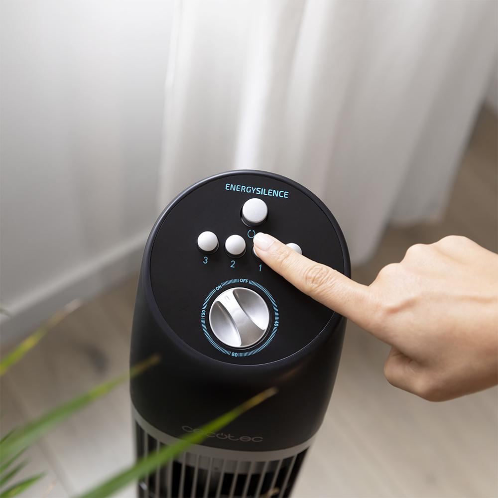 Un ventilador de torre negro con botones de control y un dedo tocando el ajuste de velocidad.